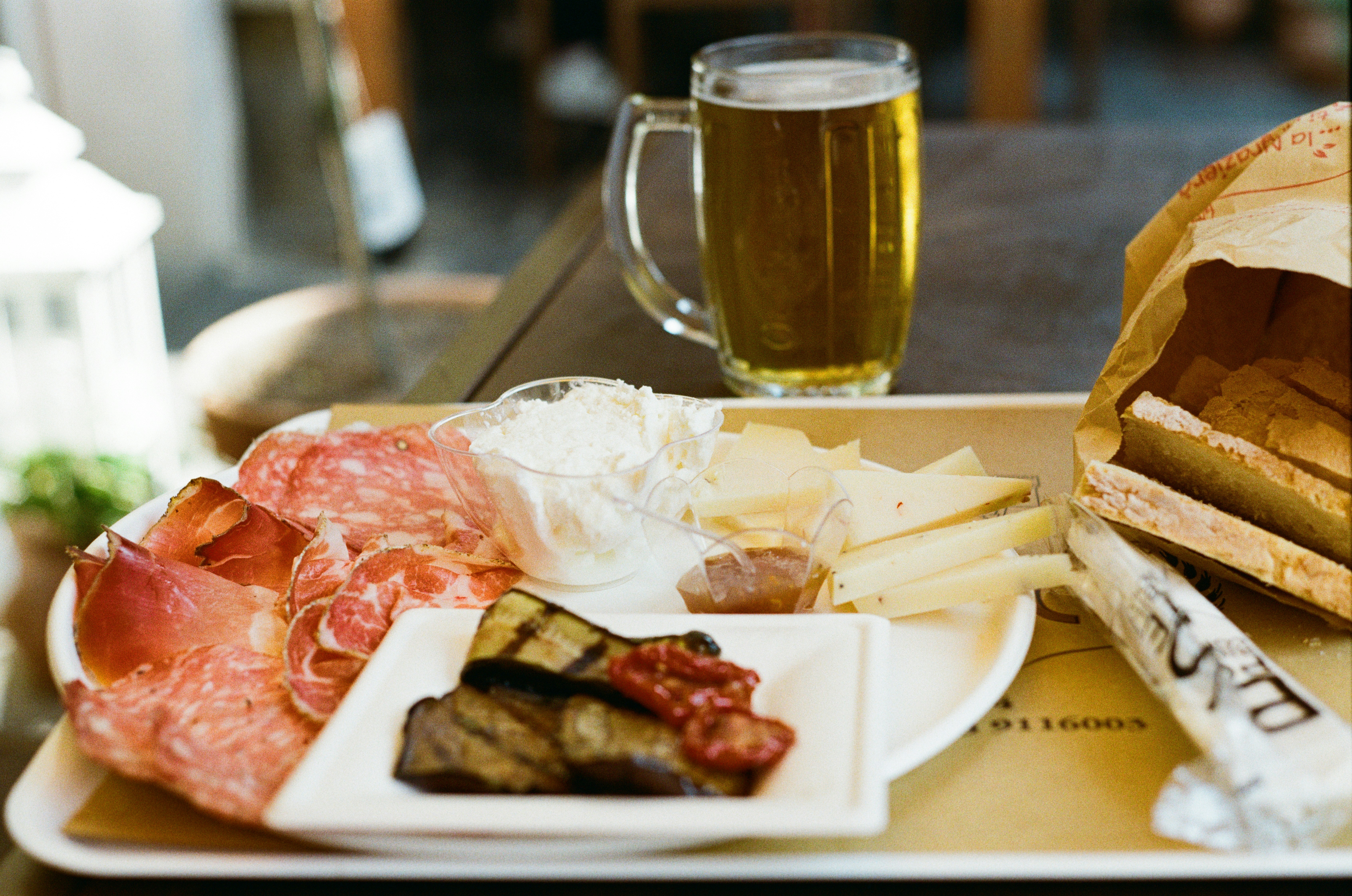 A Swiss-style platter of cured meats, cheeses and bread with a glass of beer