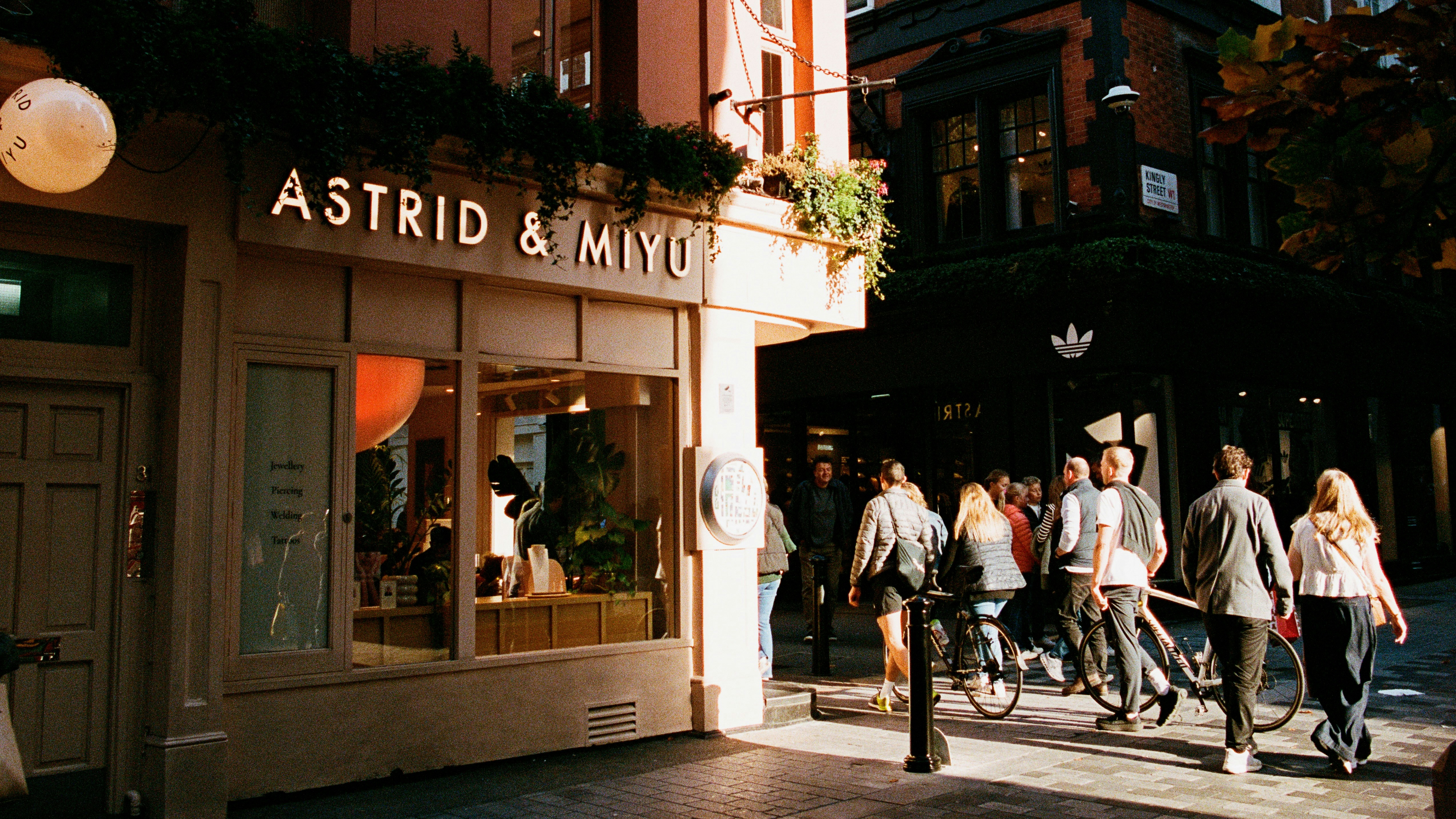 Pedestrians walk past a pink astrid & miyu store.