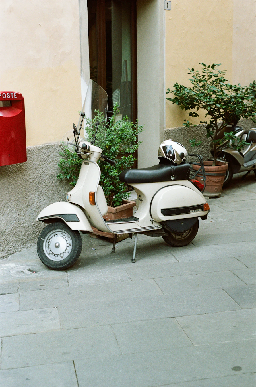 White scooter parked beside a street