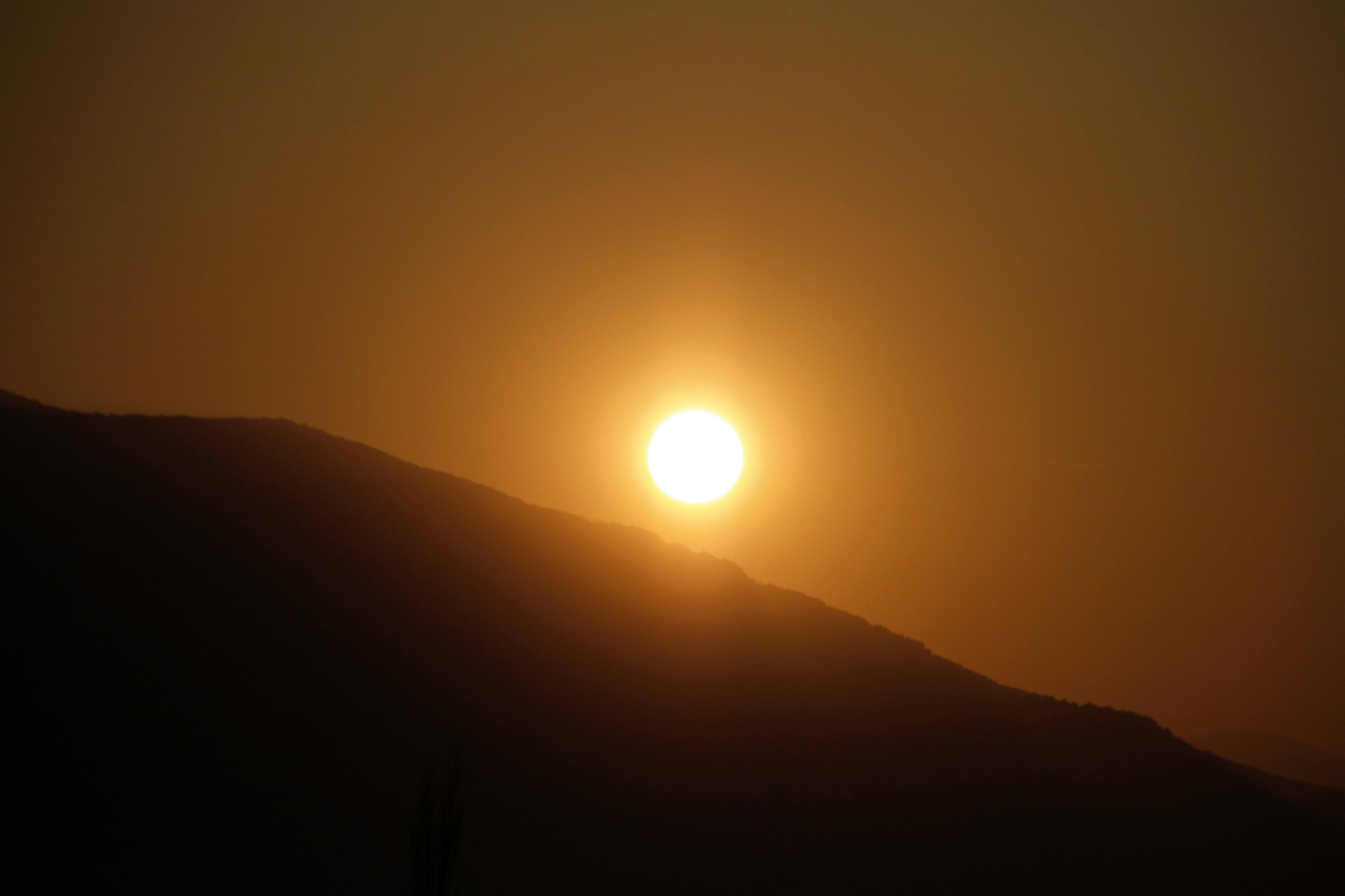 Golden sun setting over a dark mountain peak