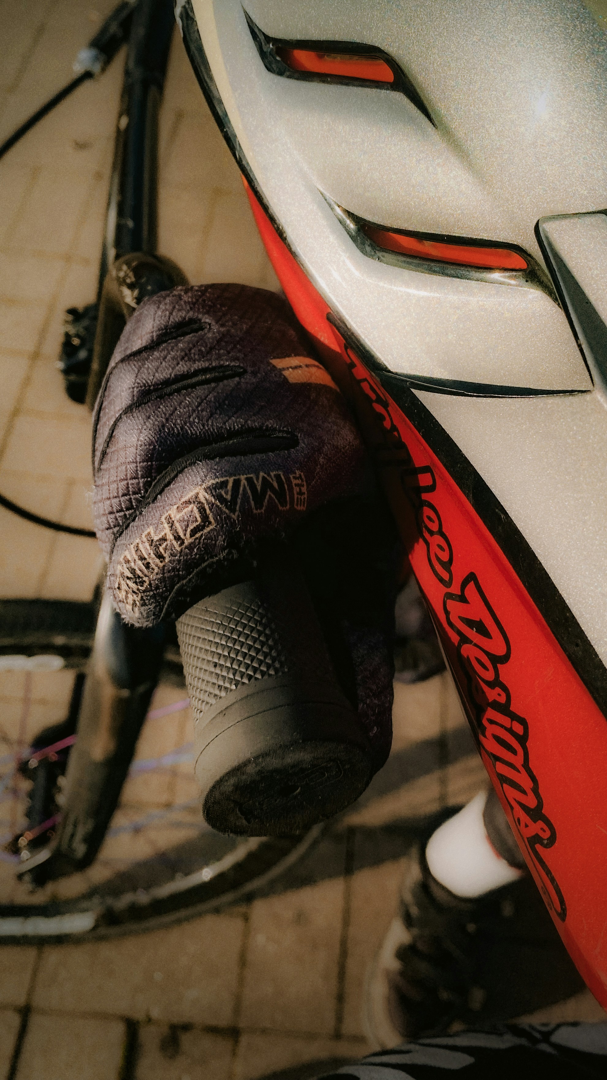 Gloved hand holding bicycle handlebar next to a helmet.