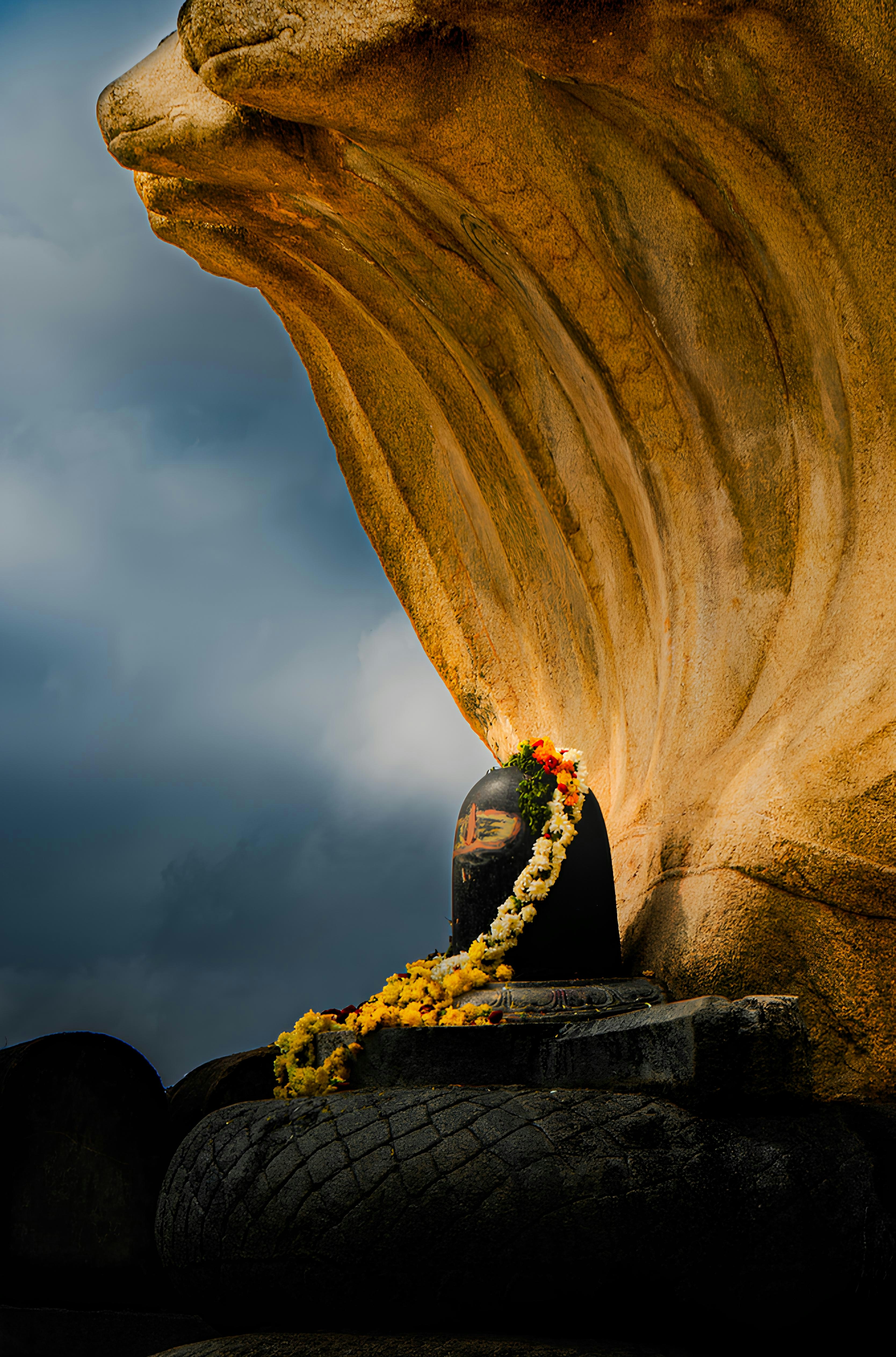 Stone cobra statue protecting a shiva lingam under dramatic sky