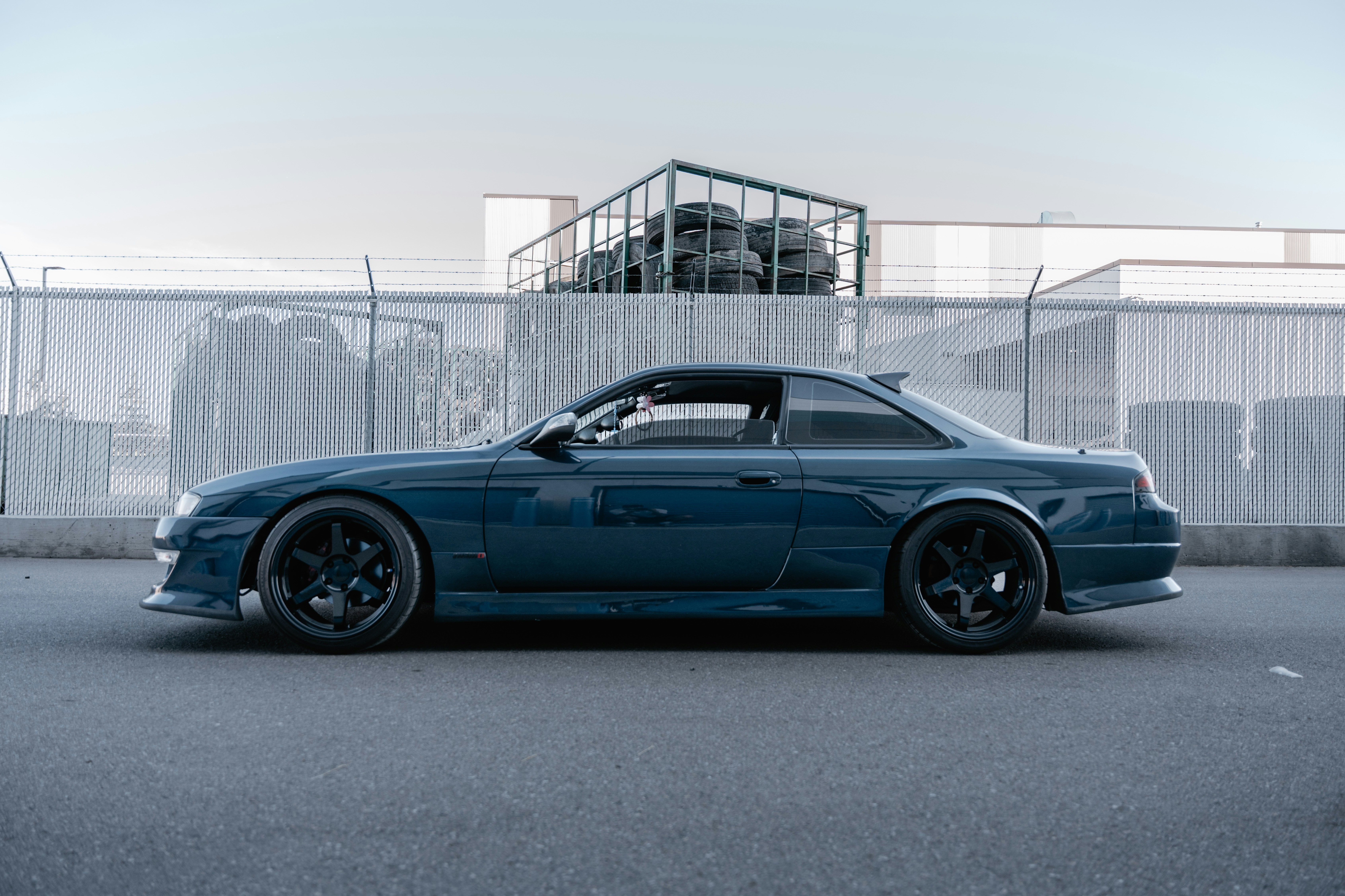 Dark blue sports car parked against an industrial background