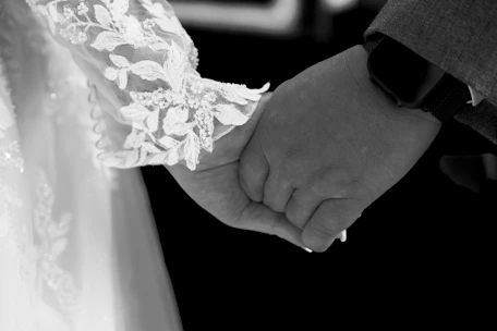 A bride and groom holding hands in black and white