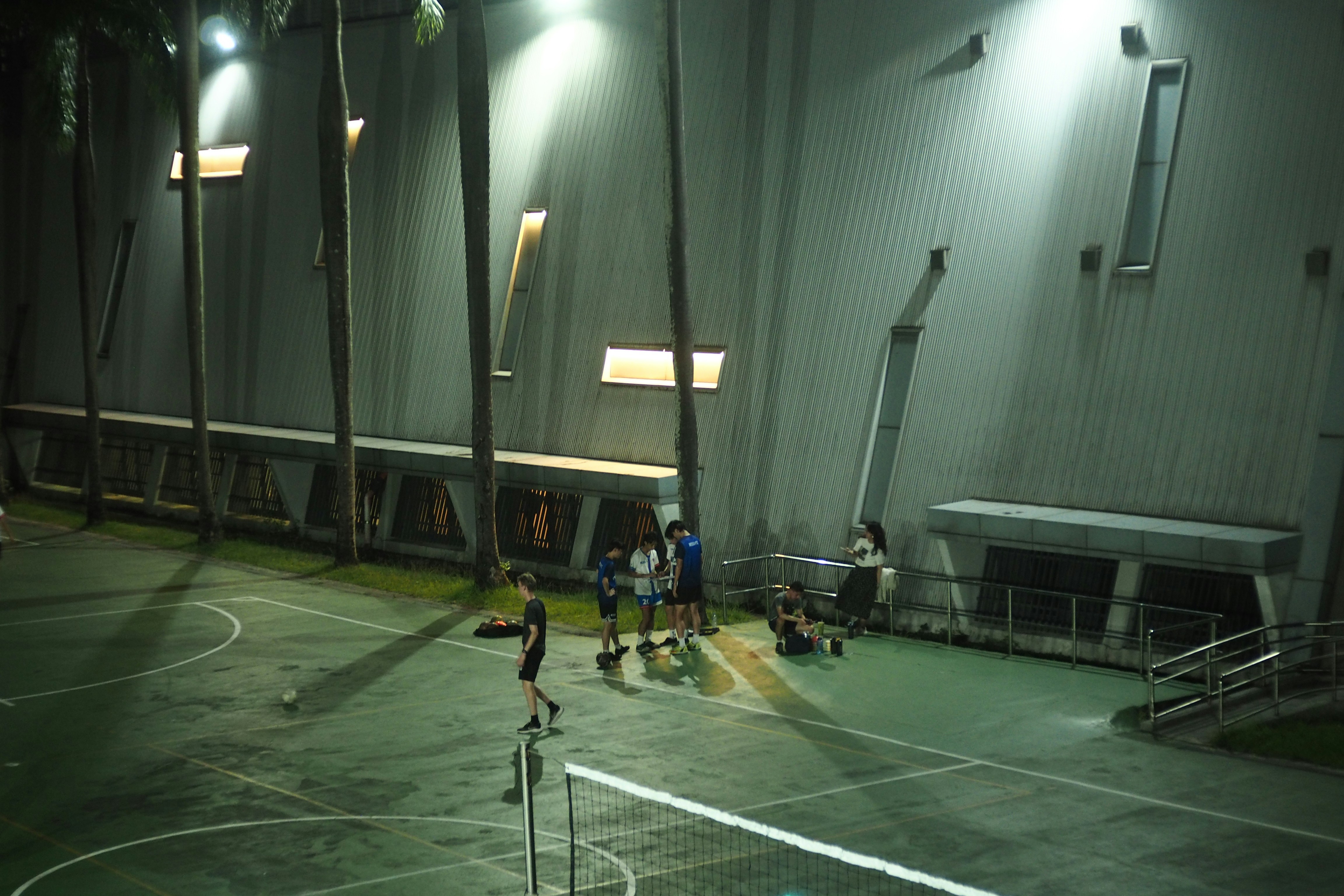 Players on an indoor court illuminated by bright overhead lights.