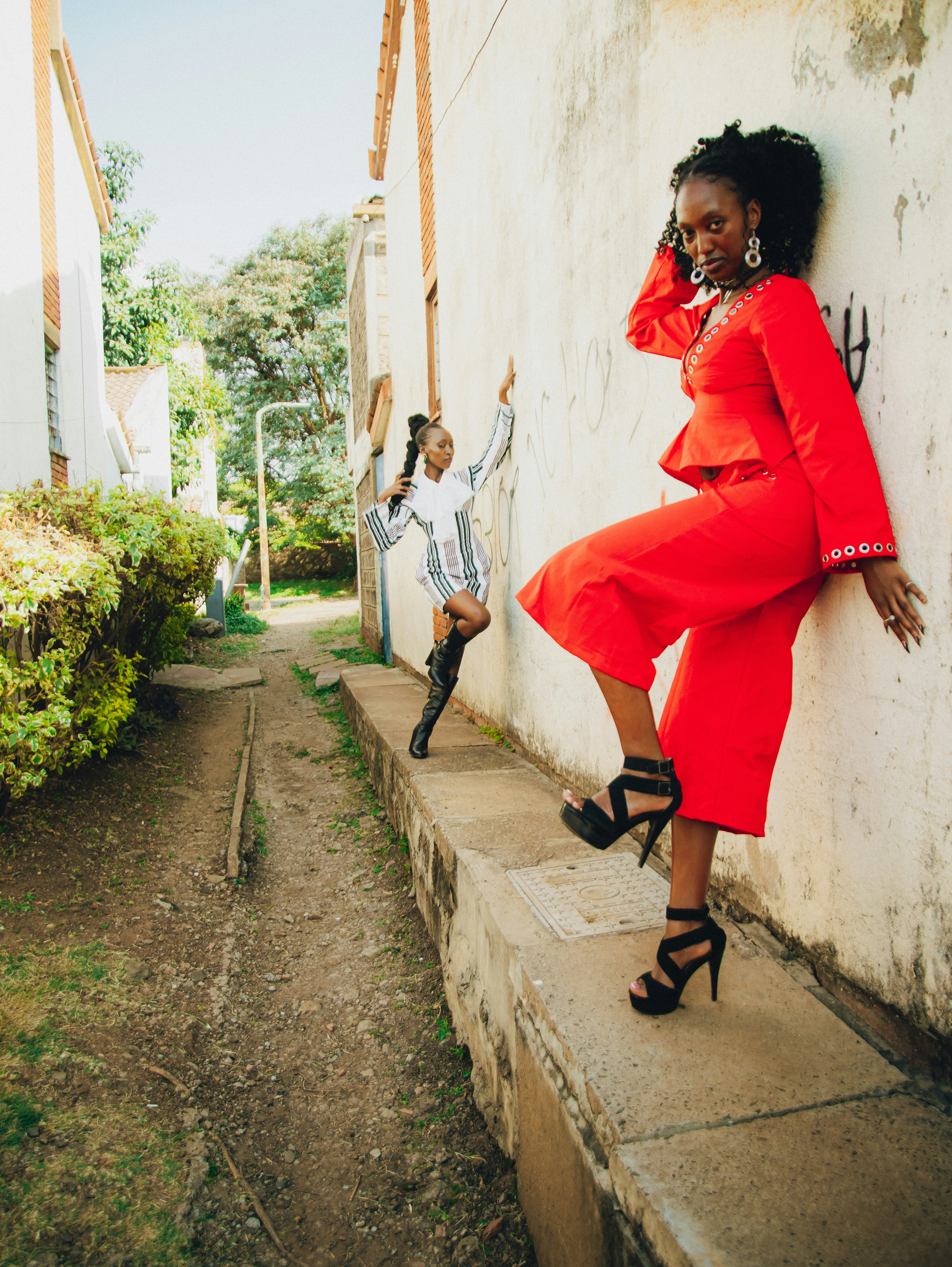 Two stylish women posing in an alleyway.