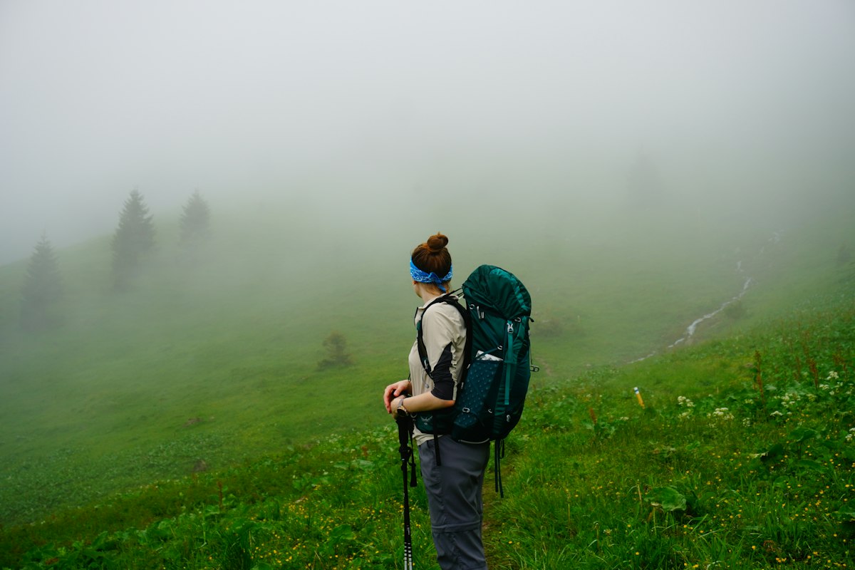 Peregrina caminando entre niebla en el tramo de monte del Camino a Muxía
