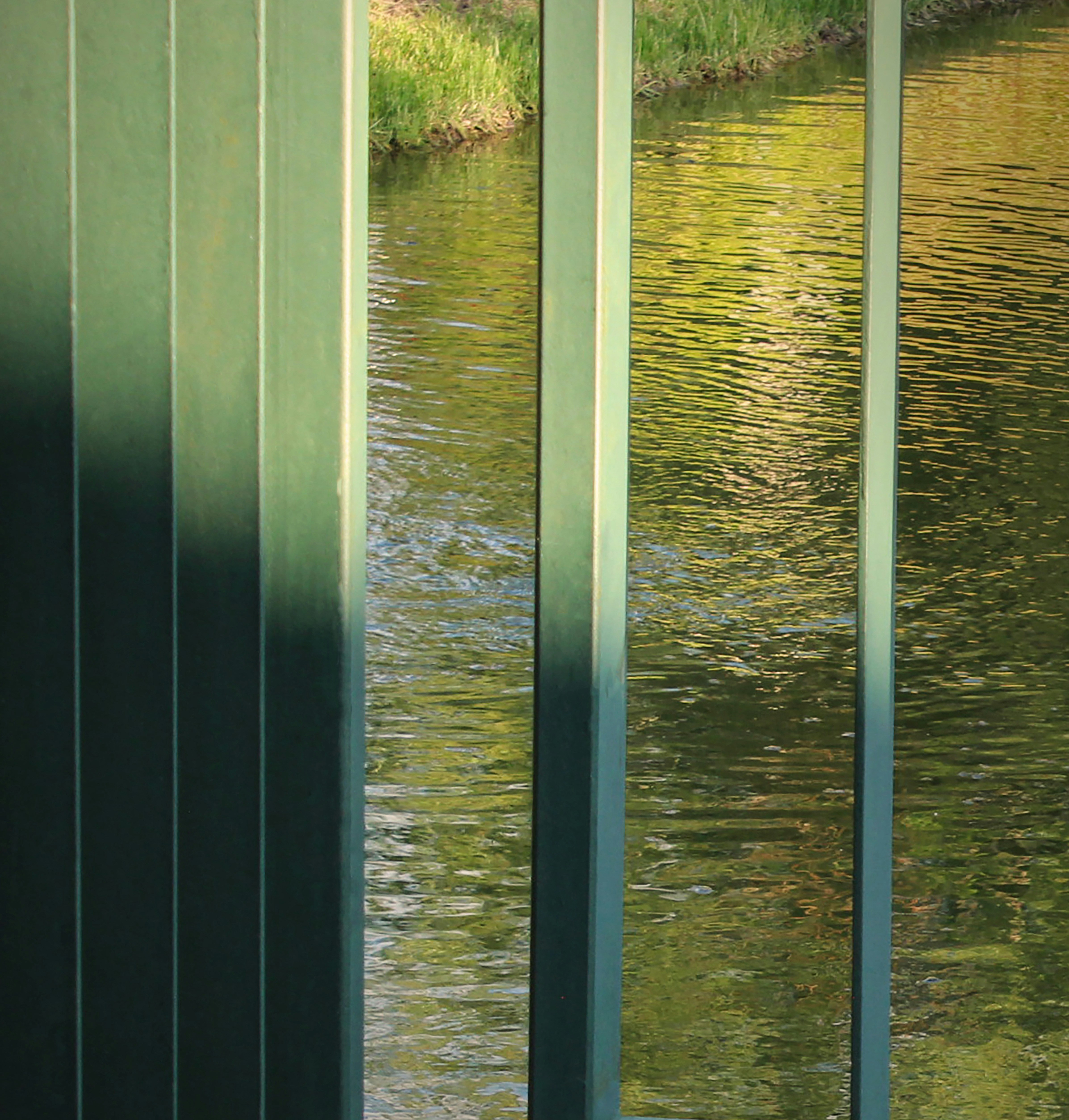 Painéis verticais verdes obscurecem parcialmente um canal refletor.