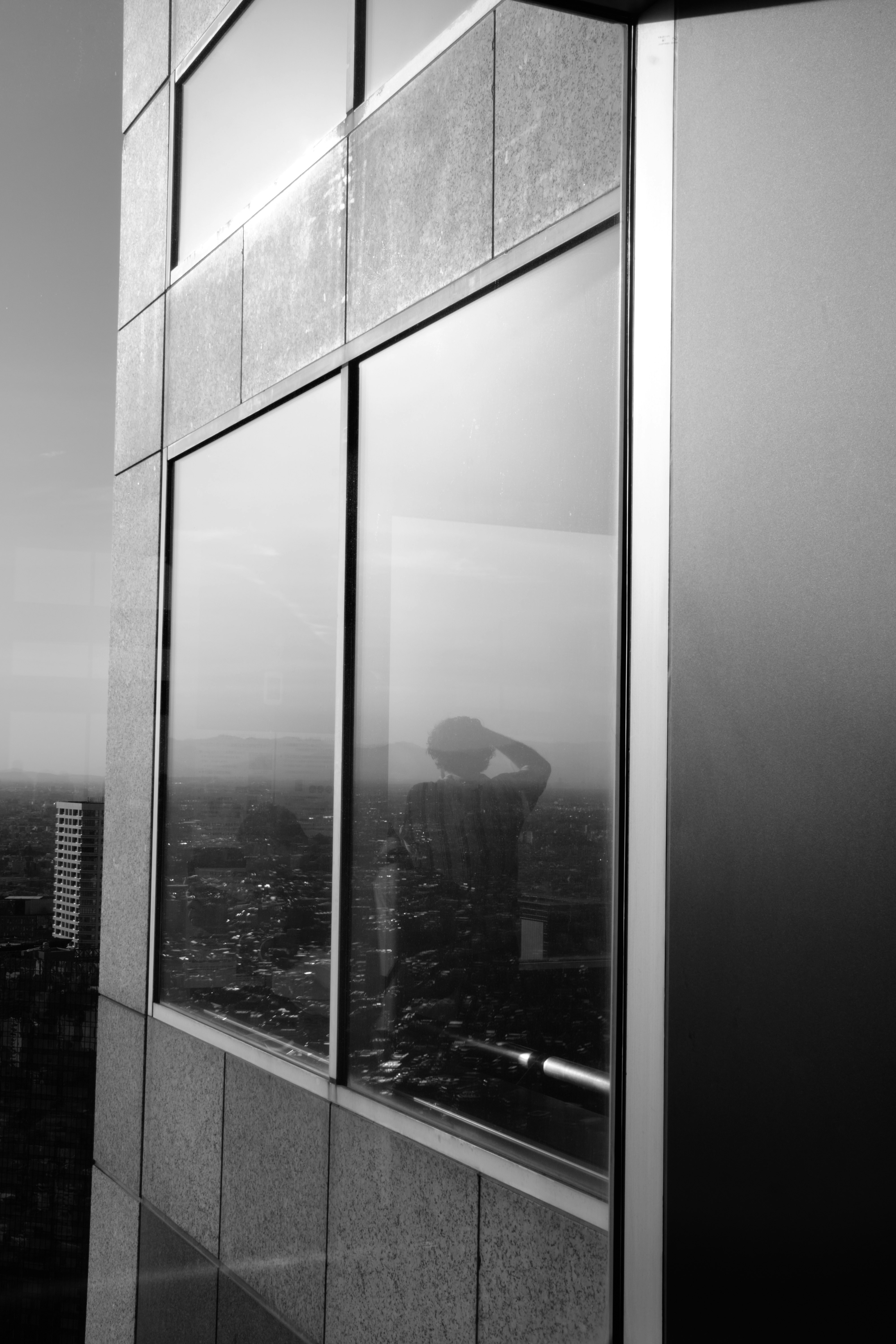 Le reflet de la personne dans une fenêtre d’immeuble donnant sur la ville.