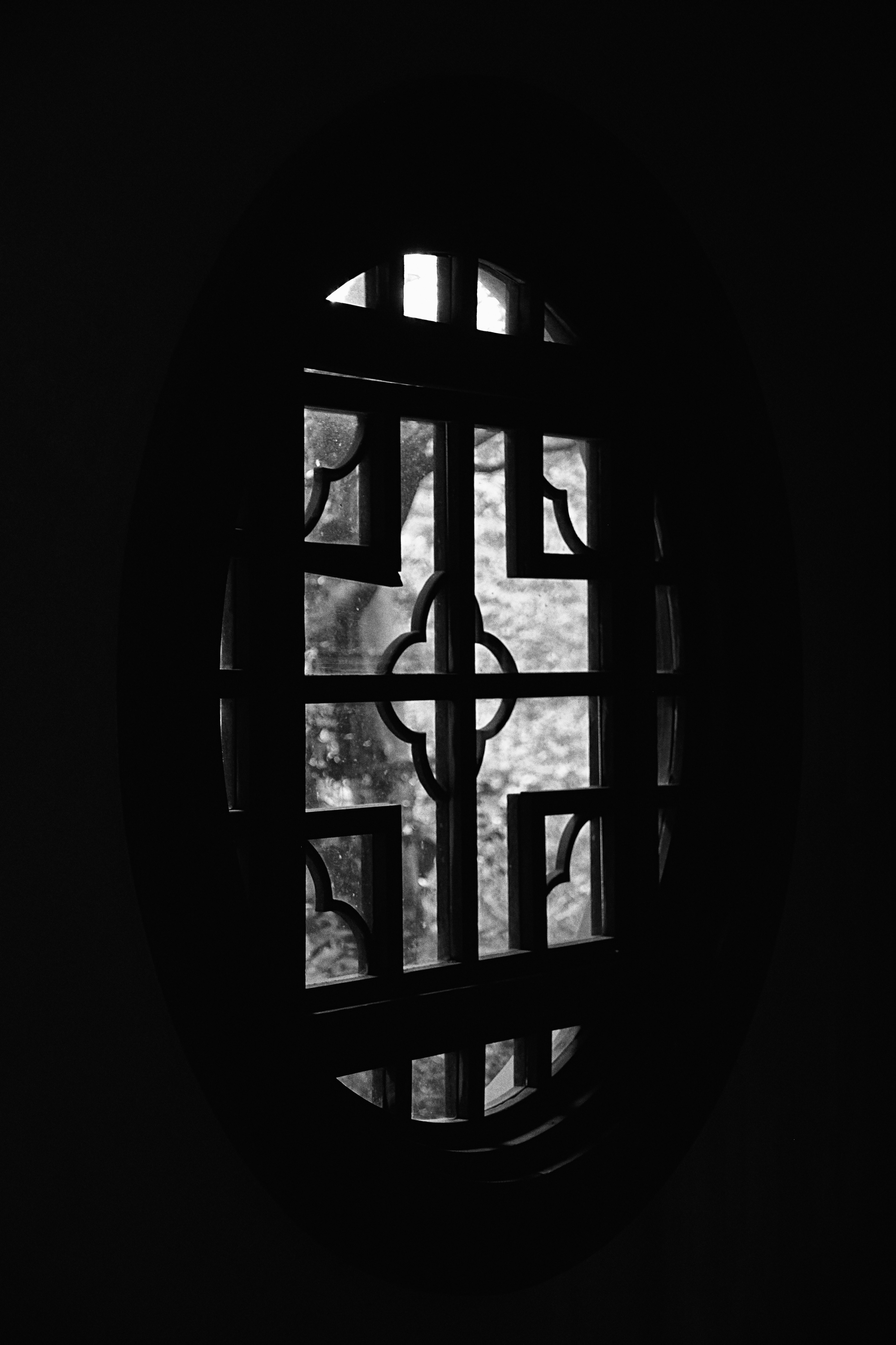 Janela oval ornamentada com padrão de treliça em preto e branco