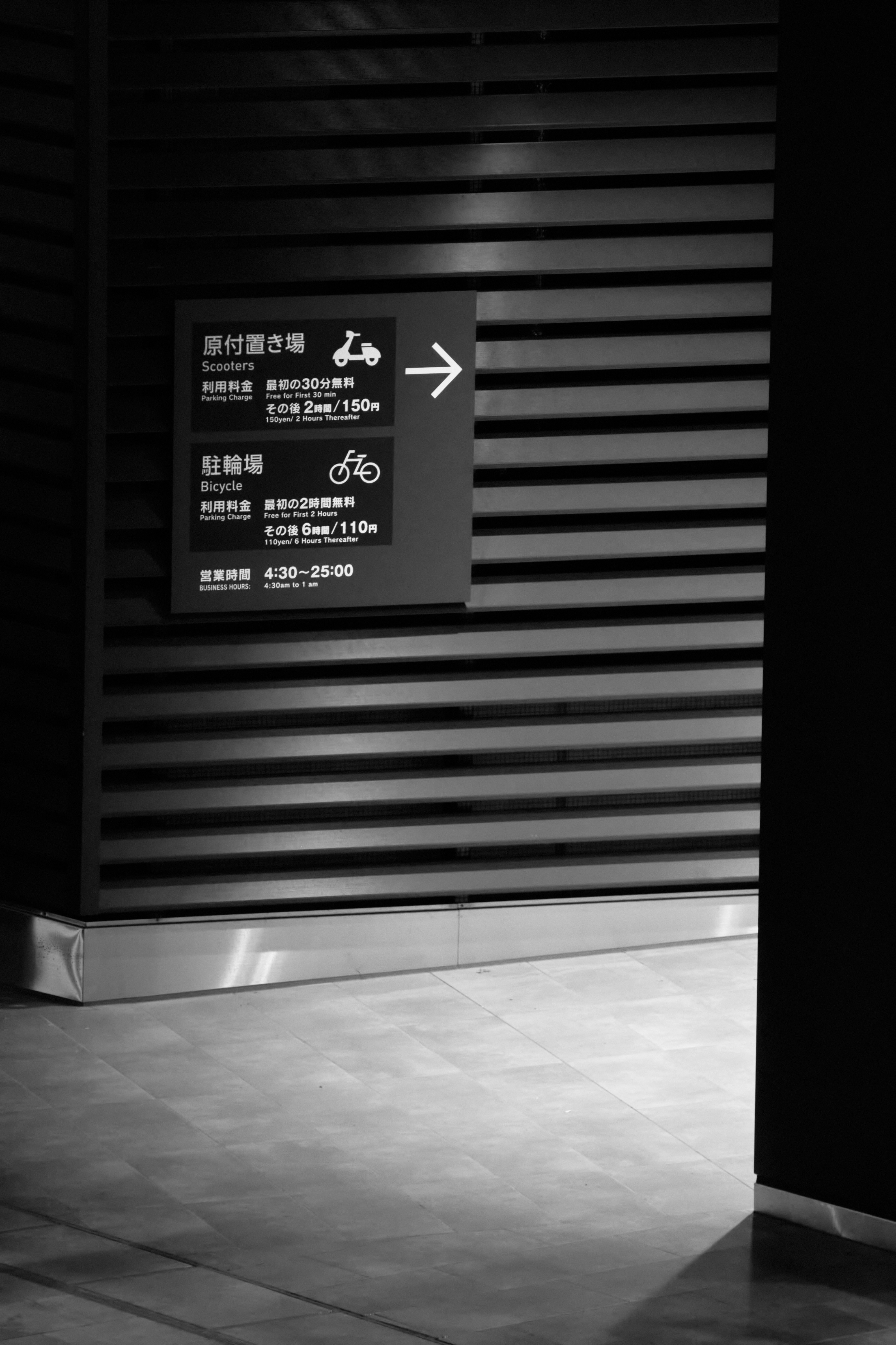 Placa de estacionamento japonesa com seta em uma parede escura com ripas de madeira