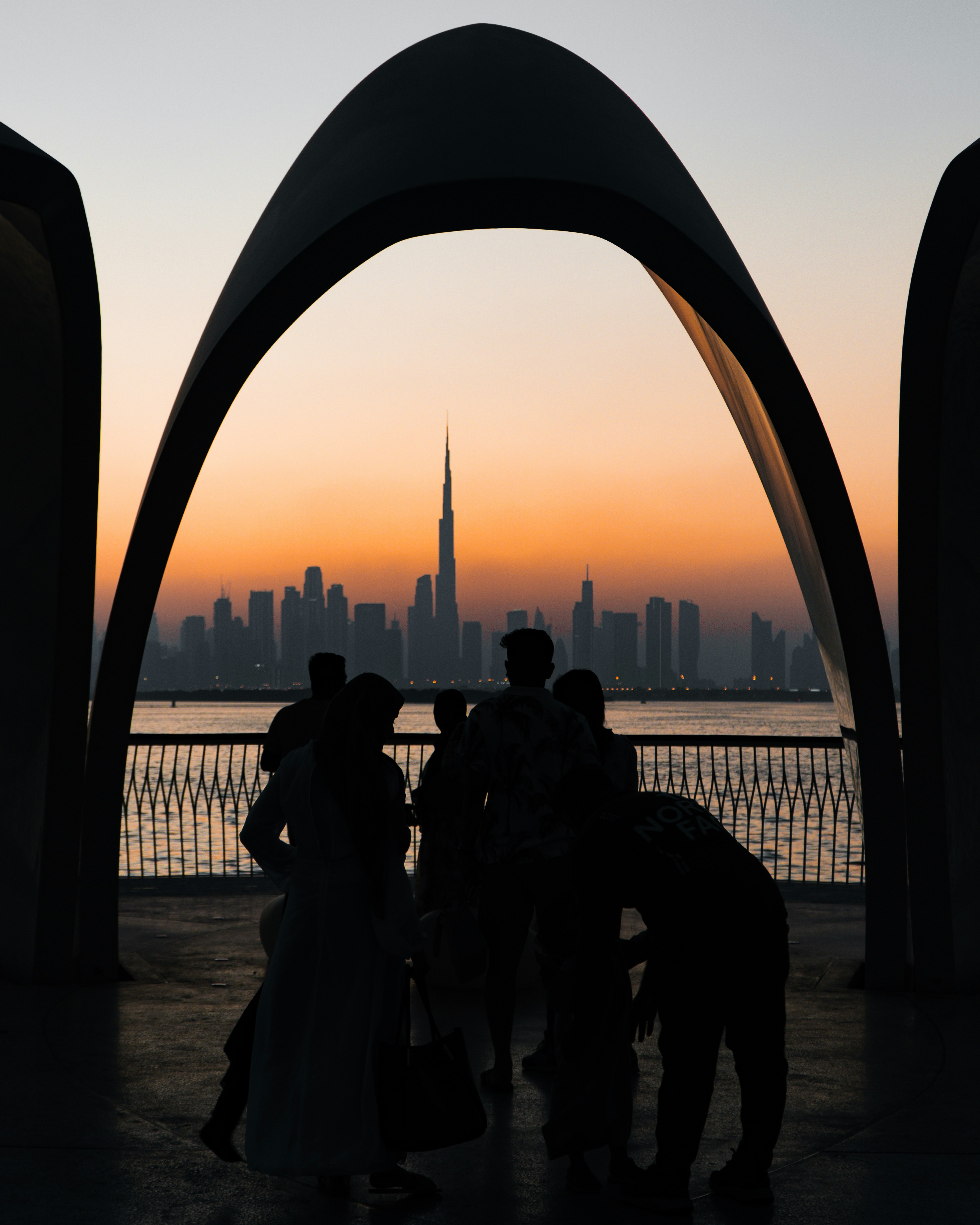 Silhouettes watch sunset over dubai skyline and burj khalifa.