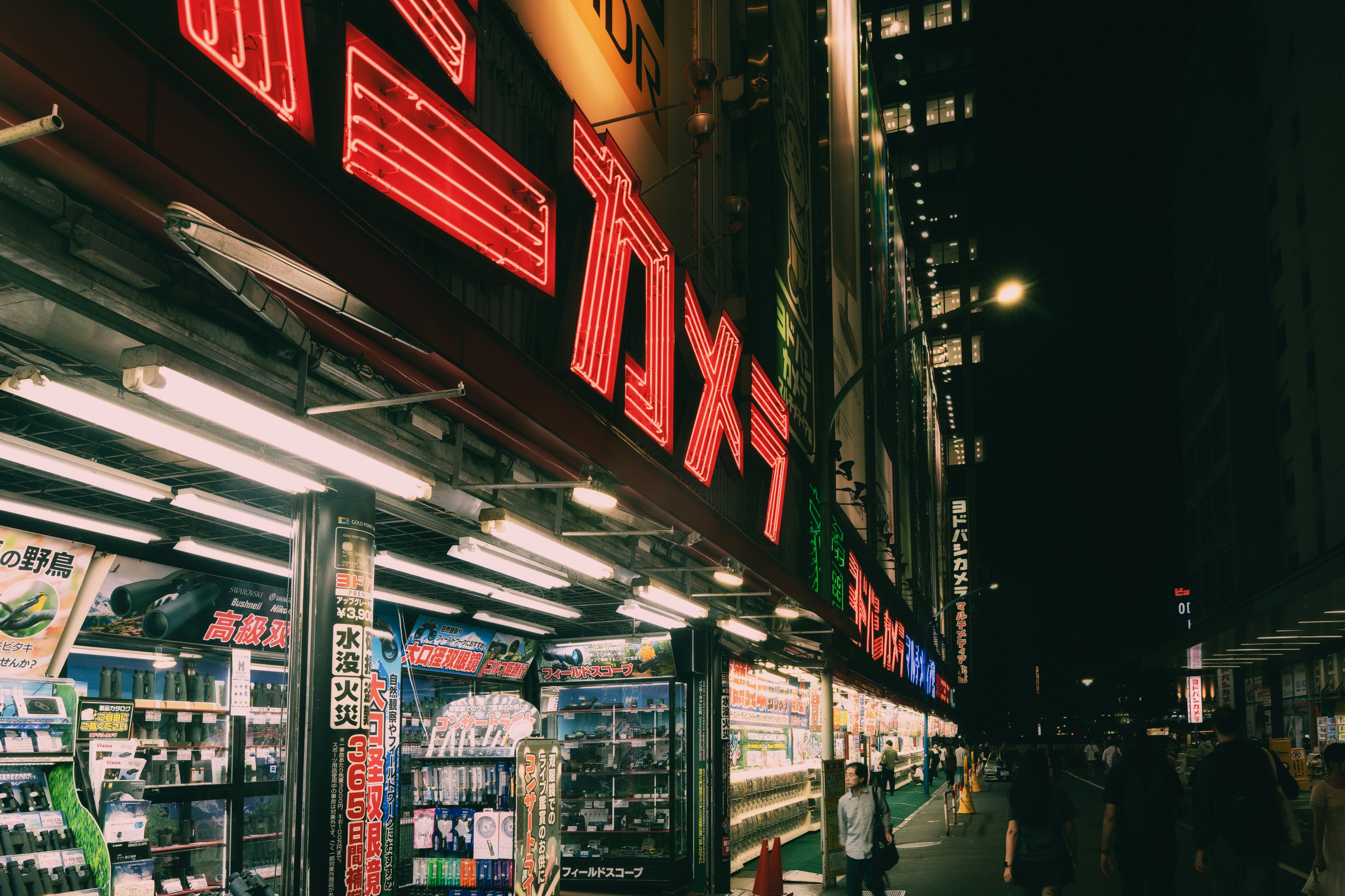 Neon signs illuminate a bustling japanese street at night.
