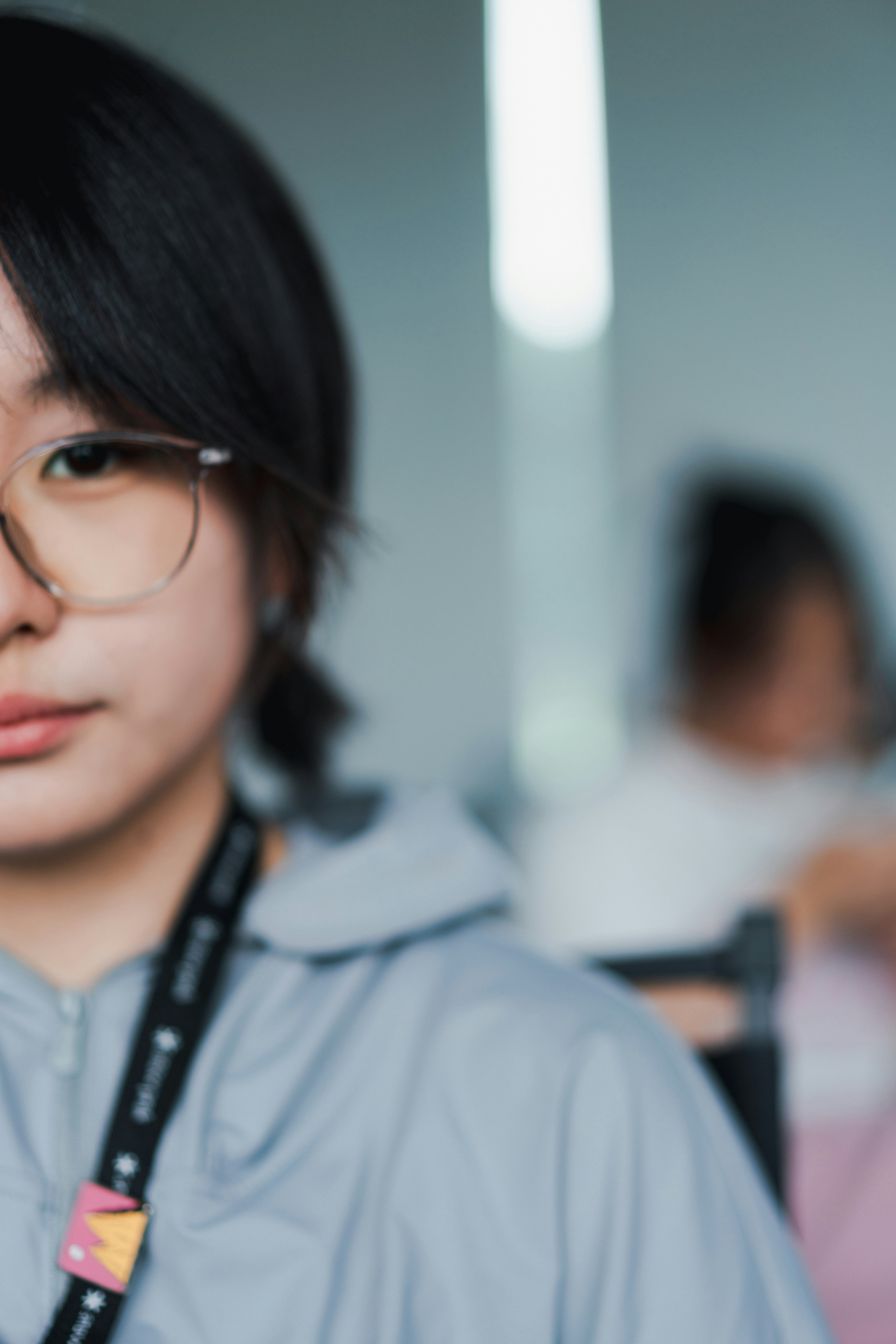 A young woman wearing glasses and a lanyard.