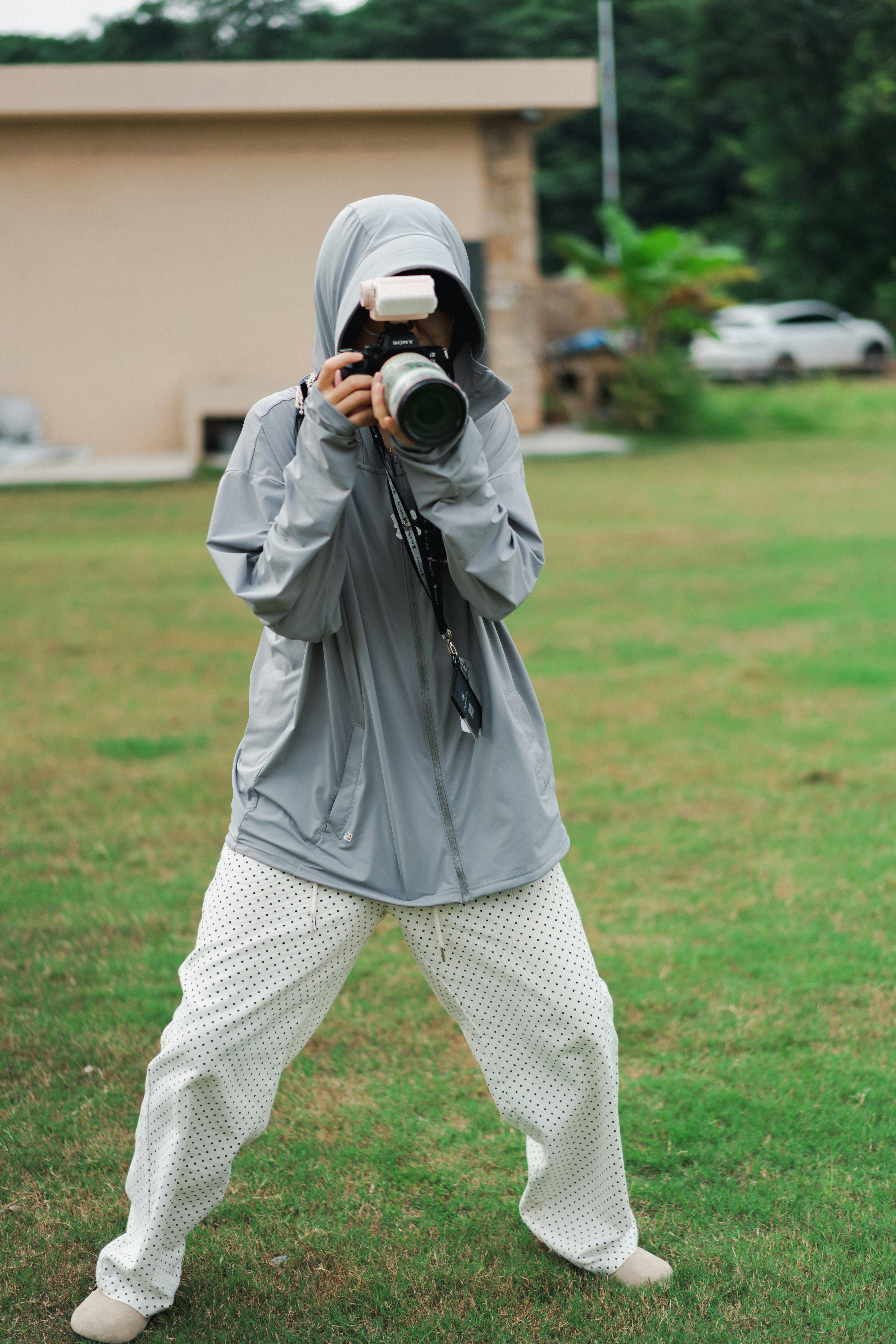 A person in a hooded jacket taking a photo outdoors.