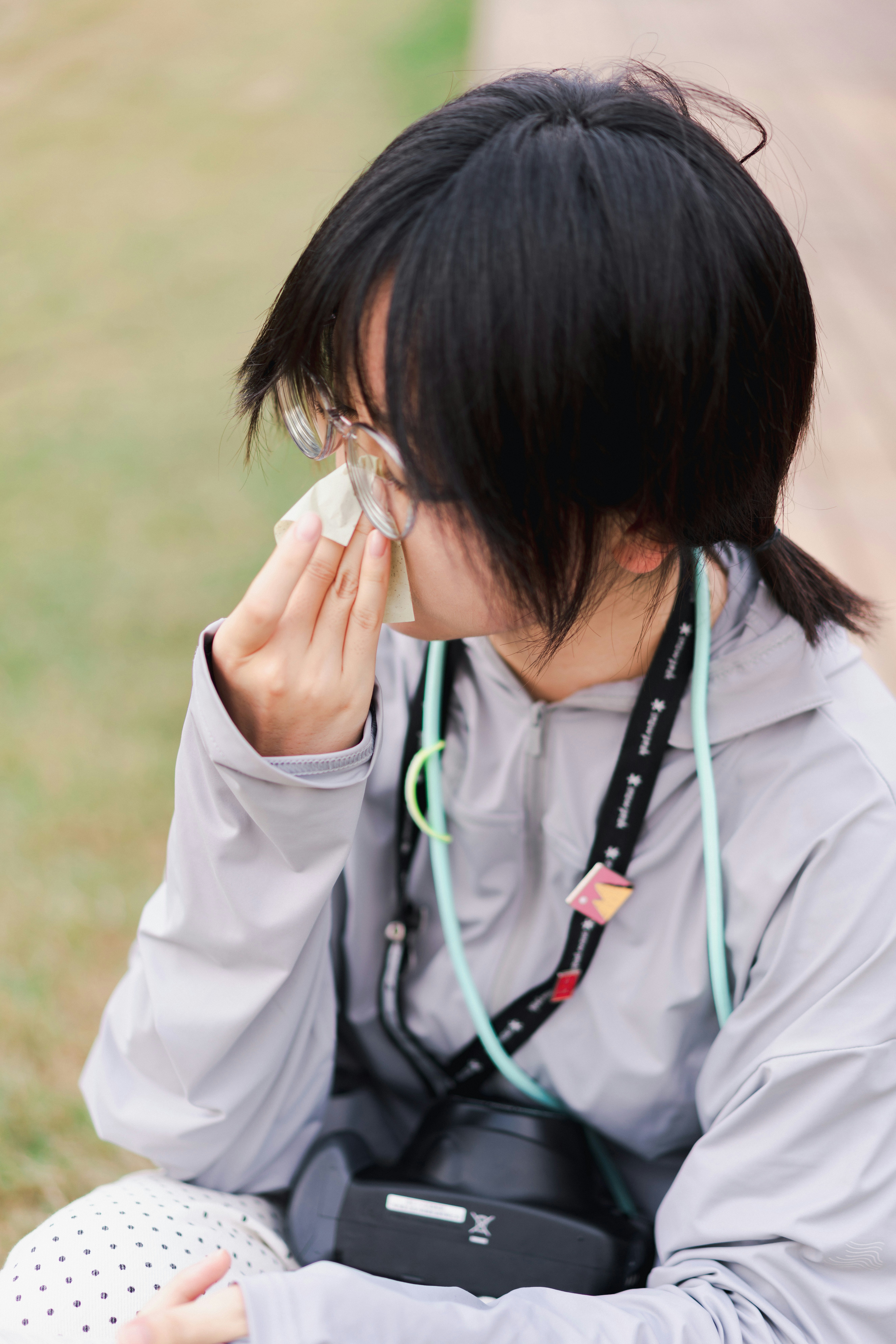 A woman in glasses wiping her nose with a tissue.