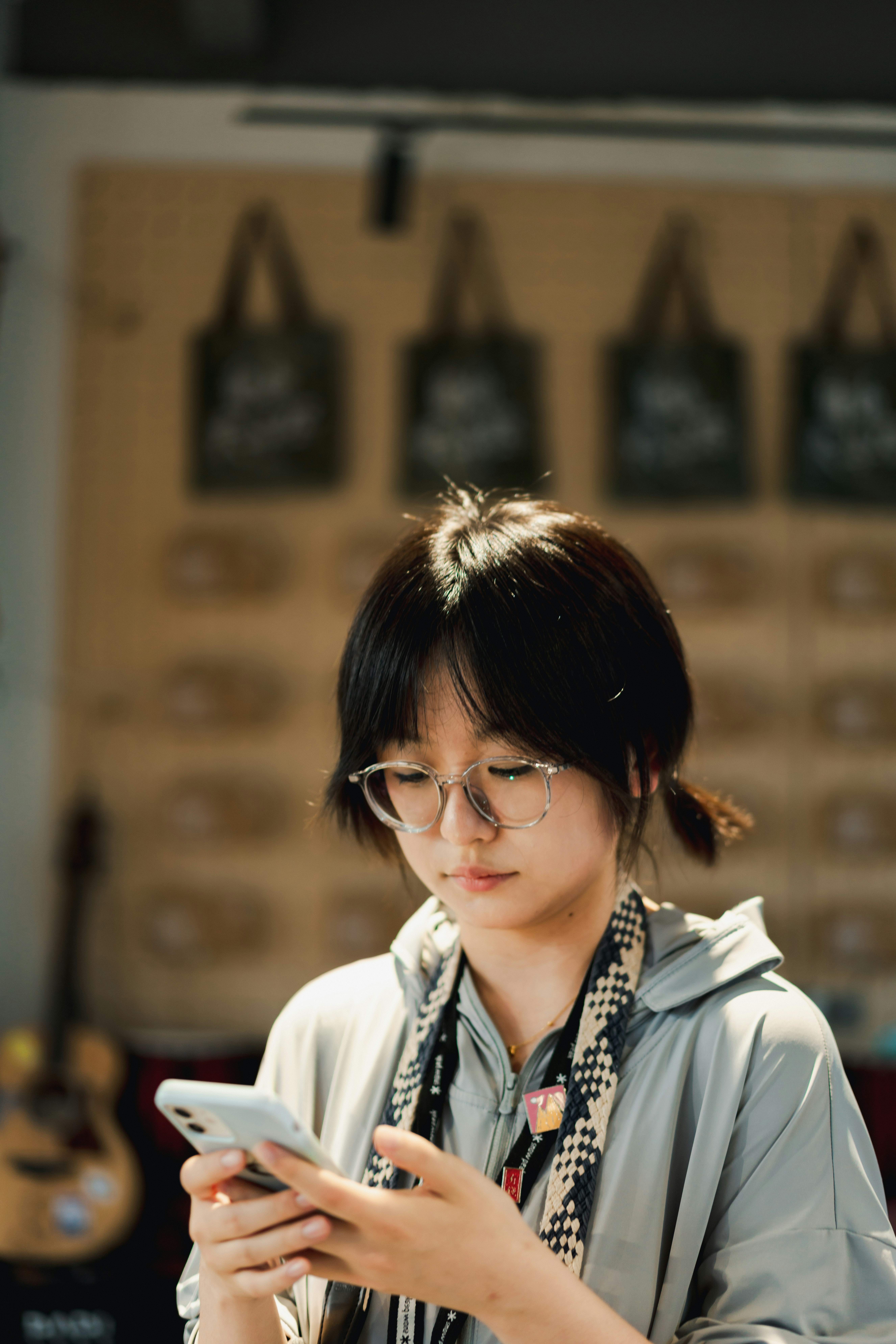 Young woman with pigtails and glasses using her phone.