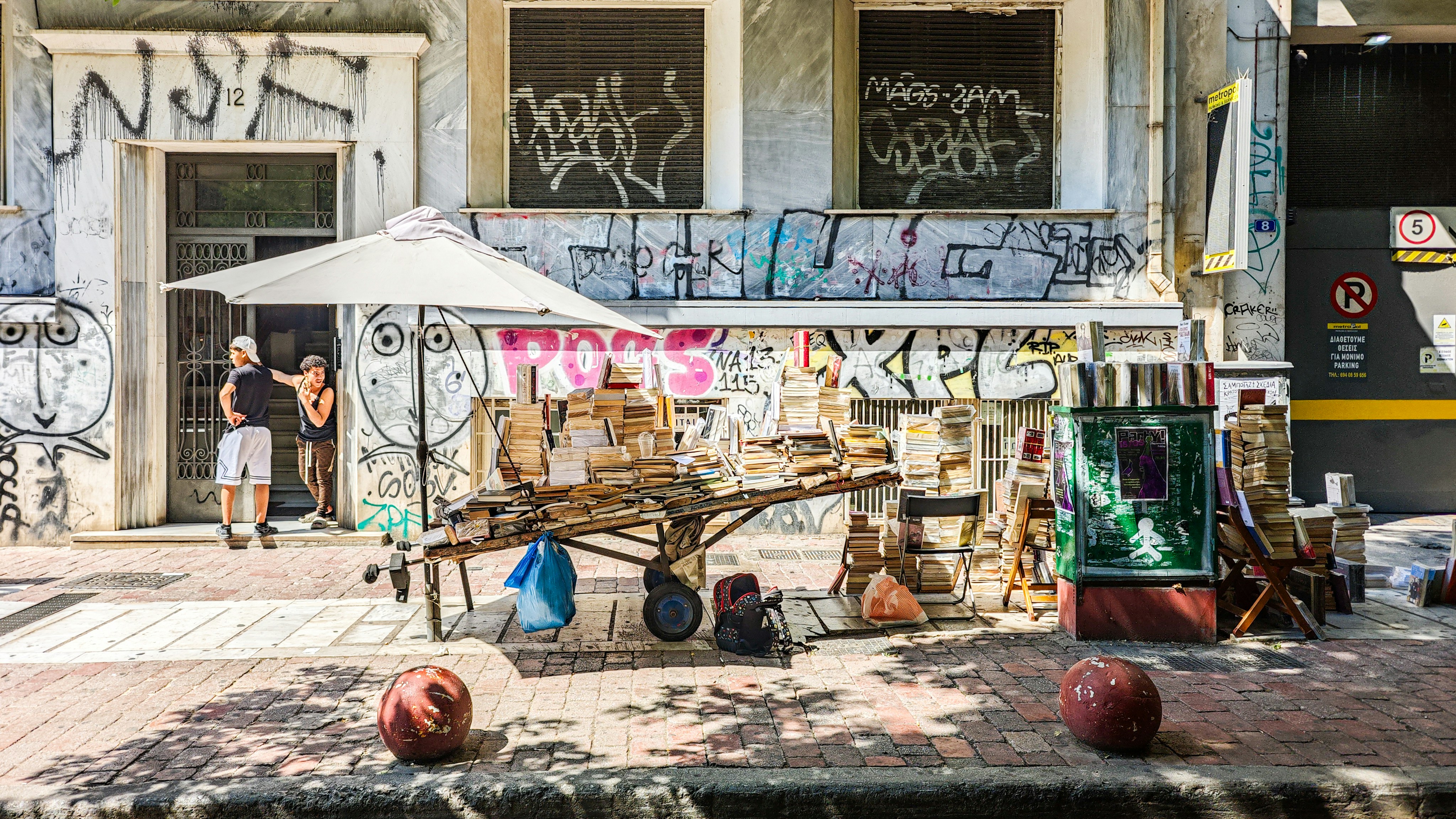 Street vendor stall with umbrella on a sunny, graffiti-covered street