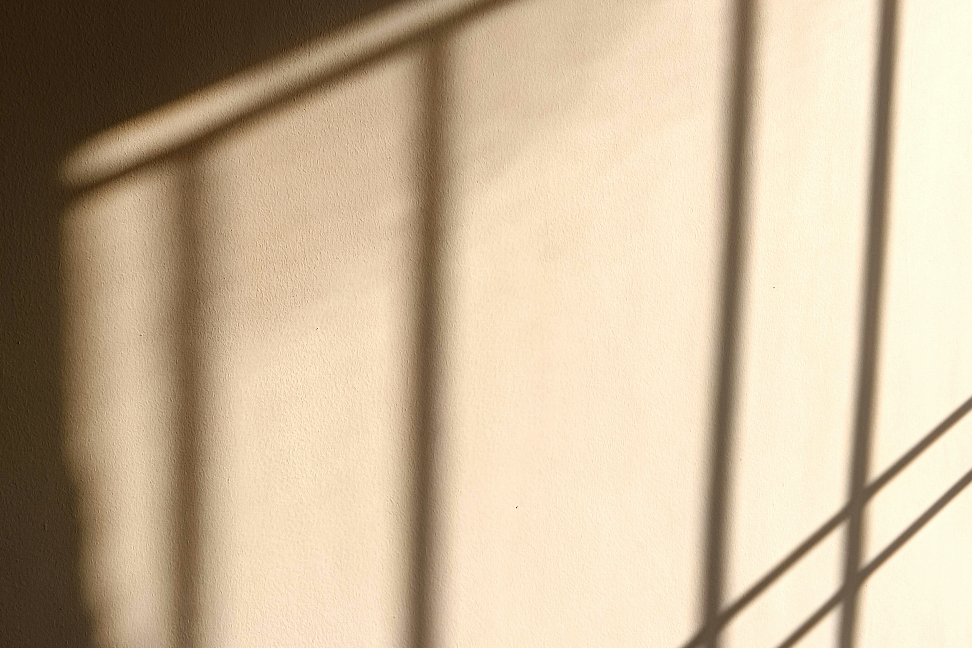 Window-frame shadows falling across a freshly plastered wall