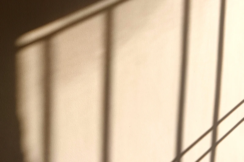 Luz do sol desenhando sombras de janela em parede clara