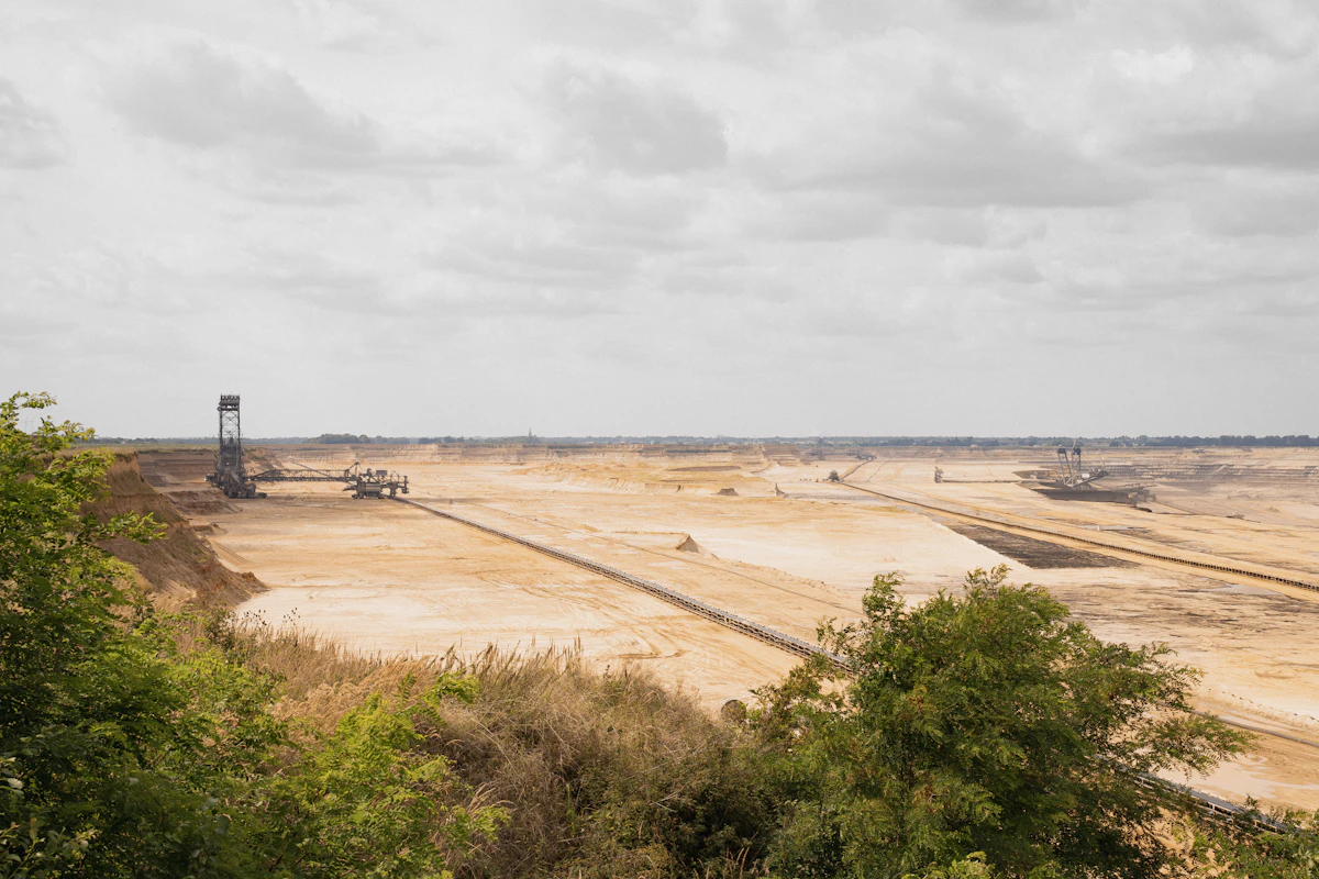 Large open-pit mine with excavators beneath a cloudy sky