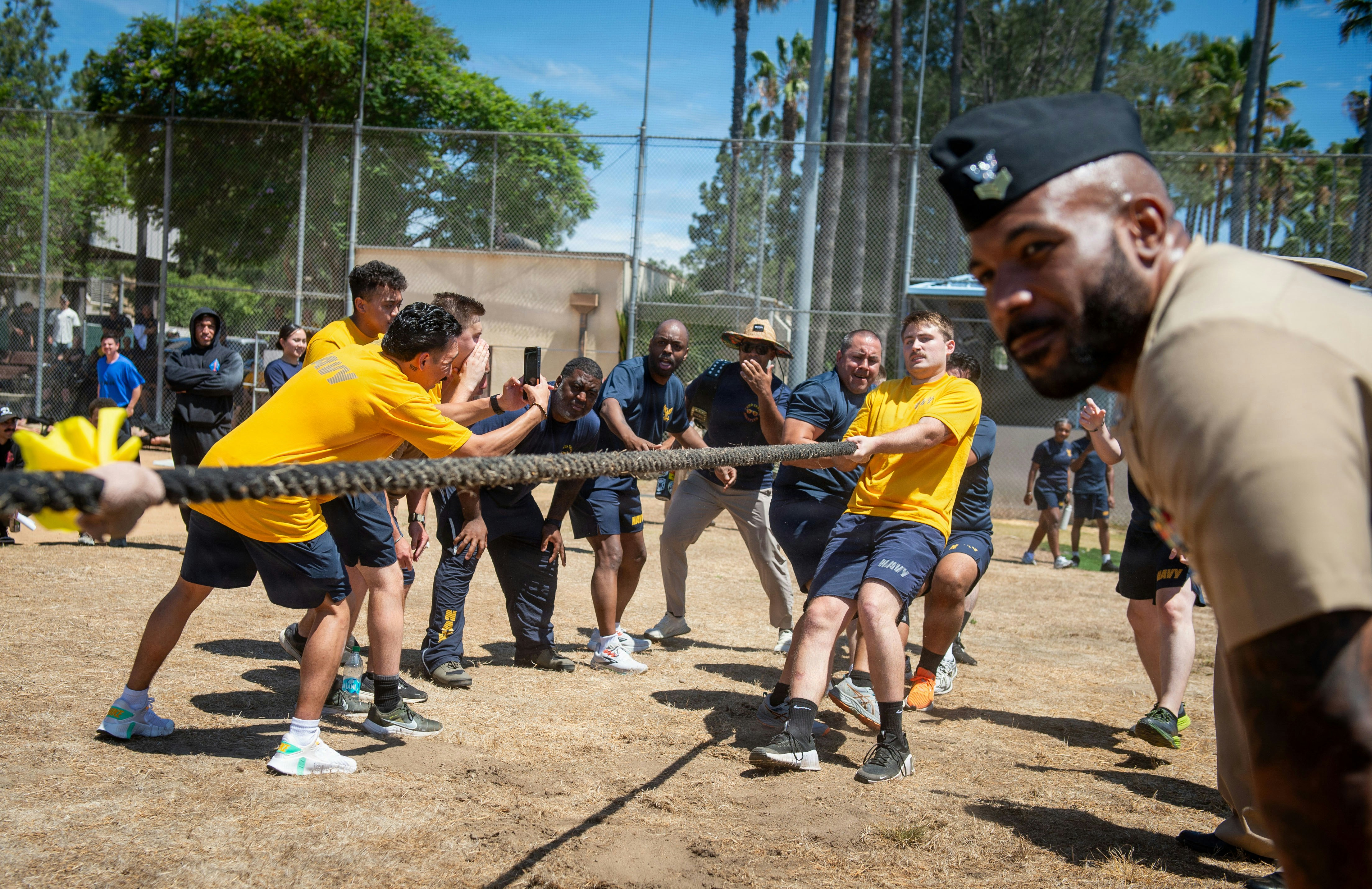 Group of adults and children playing tug-of-war outdoors.