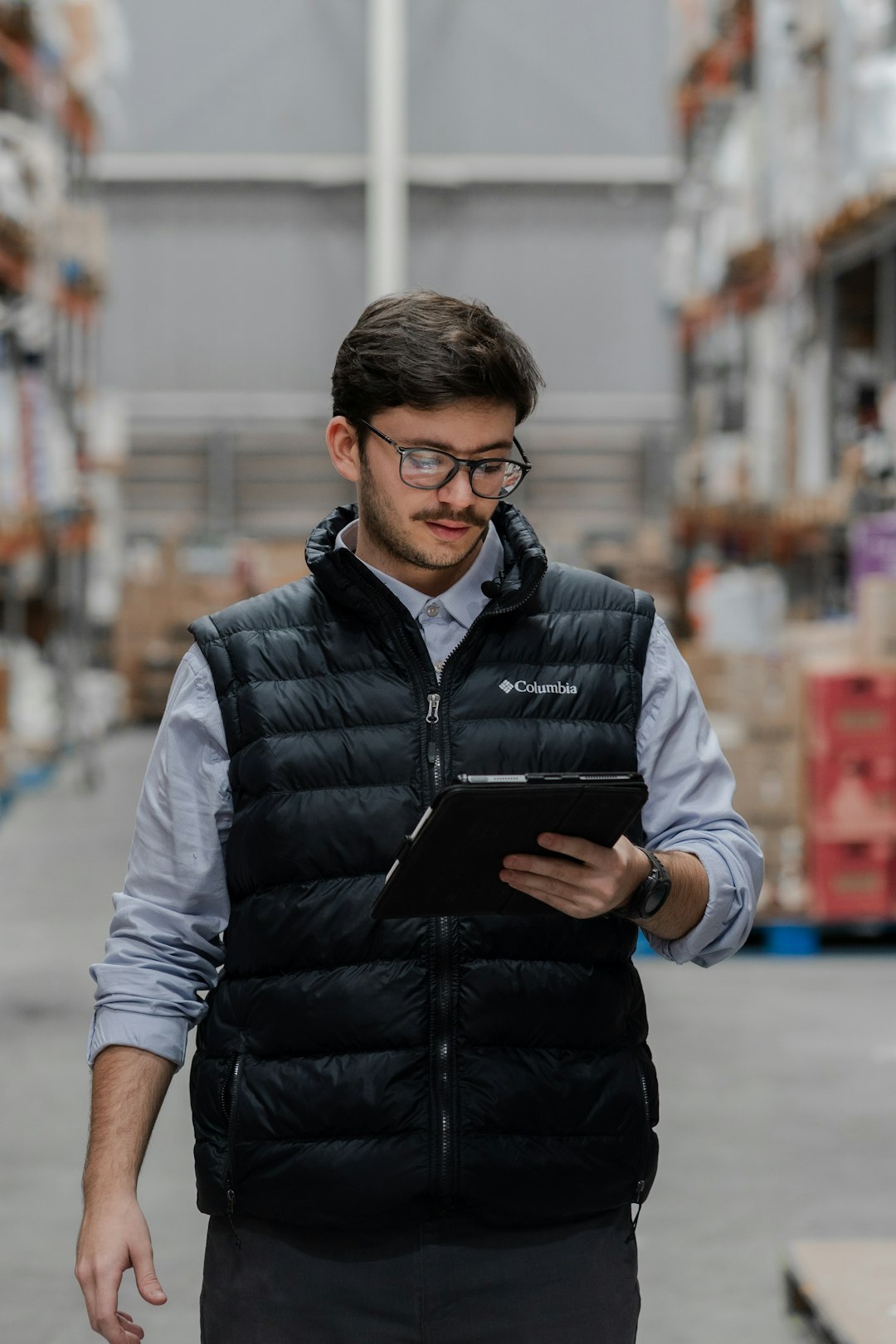 Warehouse worker in a safety vest updating records on a tablet, the daily data entry a converted workbook app takes over