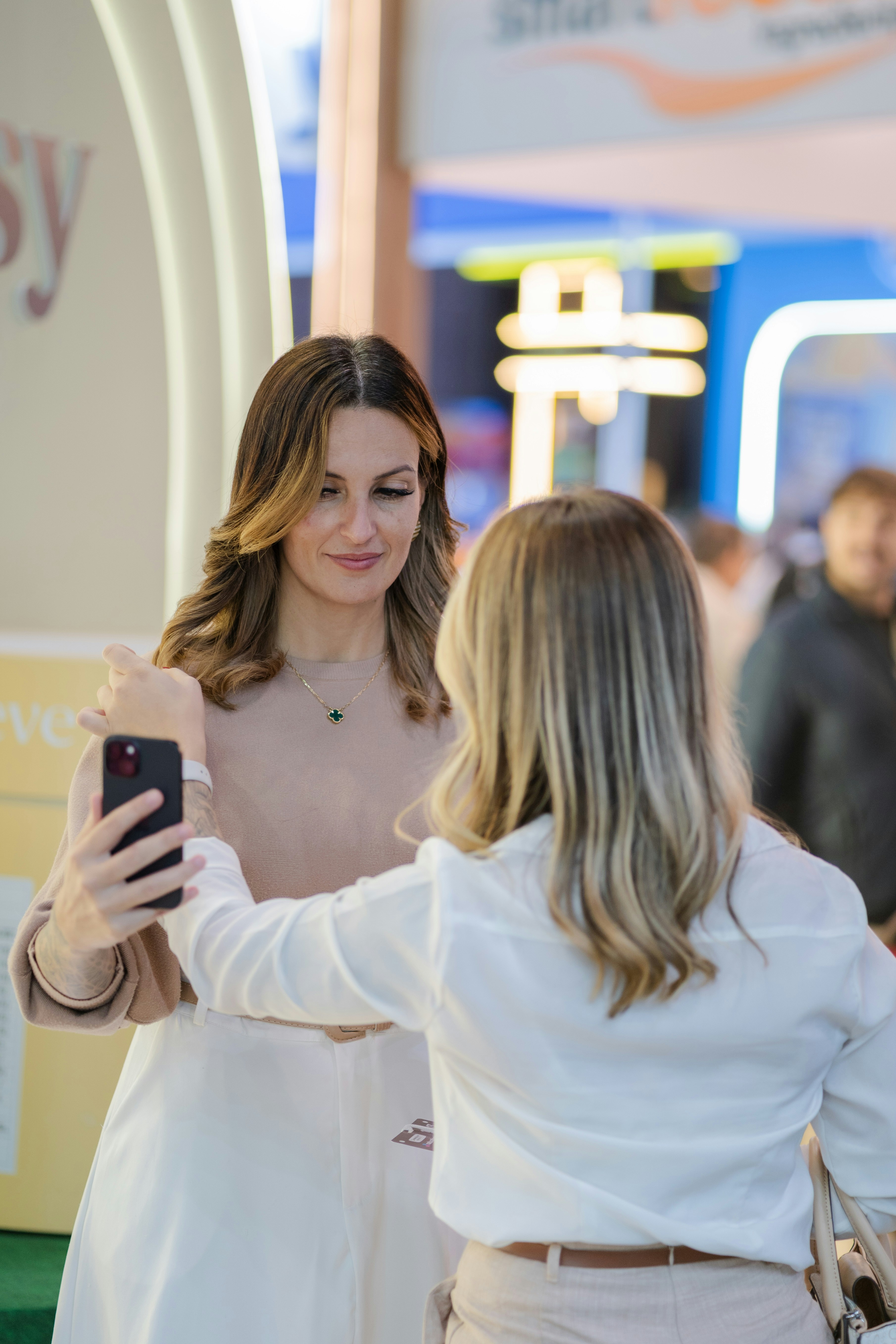 Dos mujeres haciéndose un selfie en interiores en un evento.