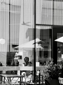 Person visible through window with reflections and outdoor seating.