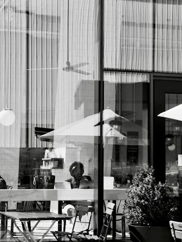 Person visible through window with reflections and outdoor seating.