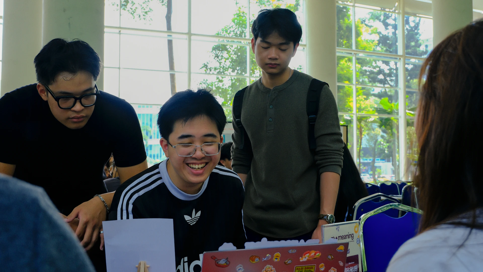 Three young men laughing and working together indoors.