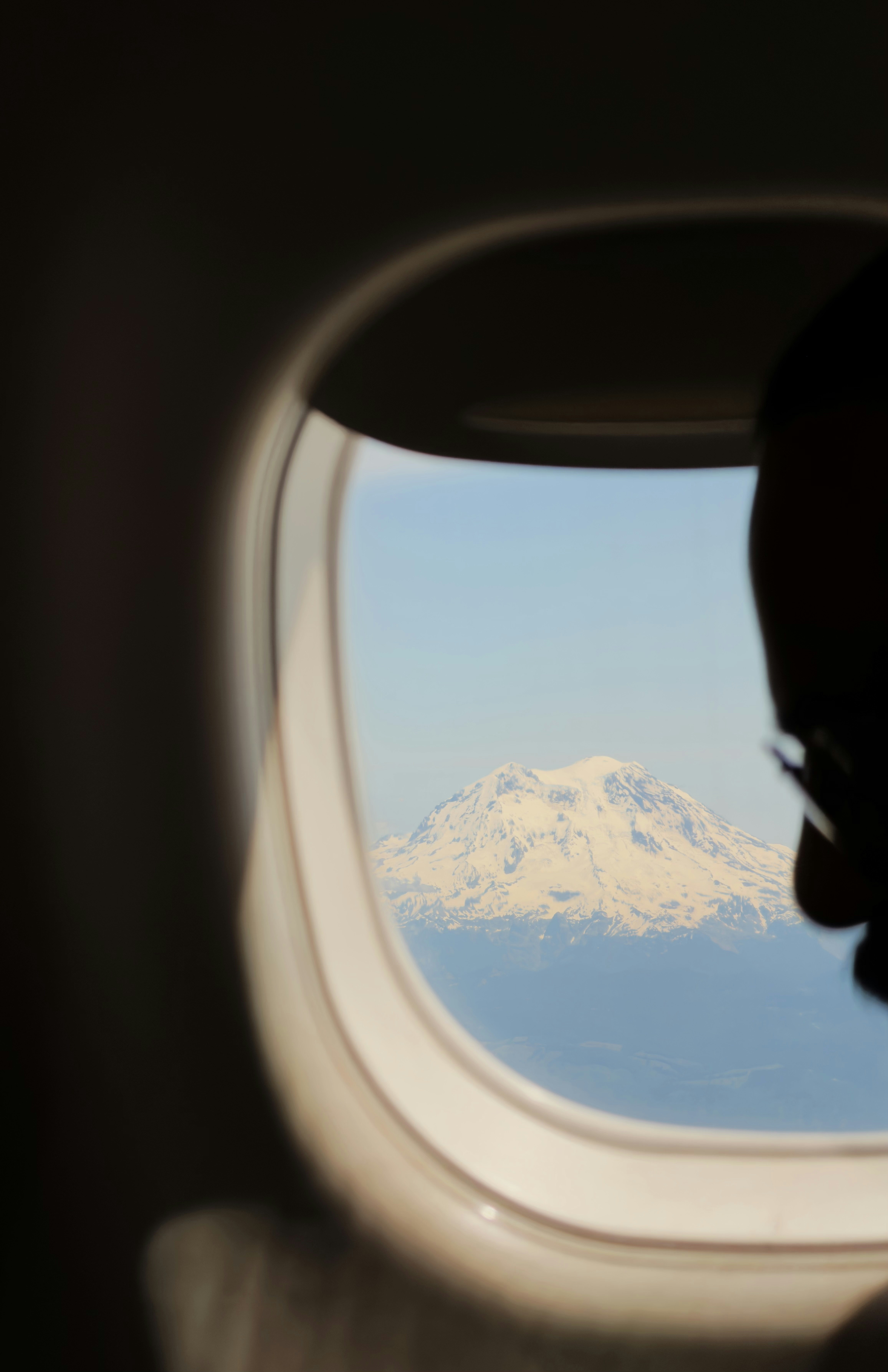 Passenger views snow-capped mountain from airplane window.