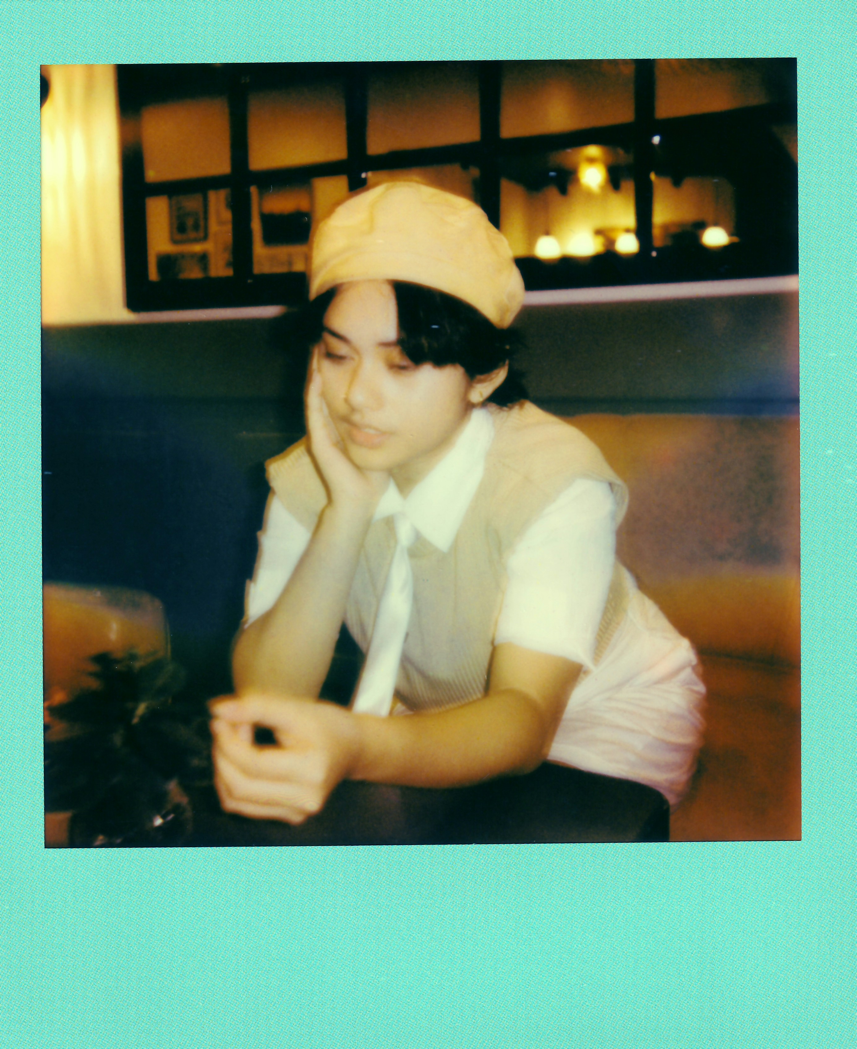 Thoughtful person in a beret sitting at a cafe table.