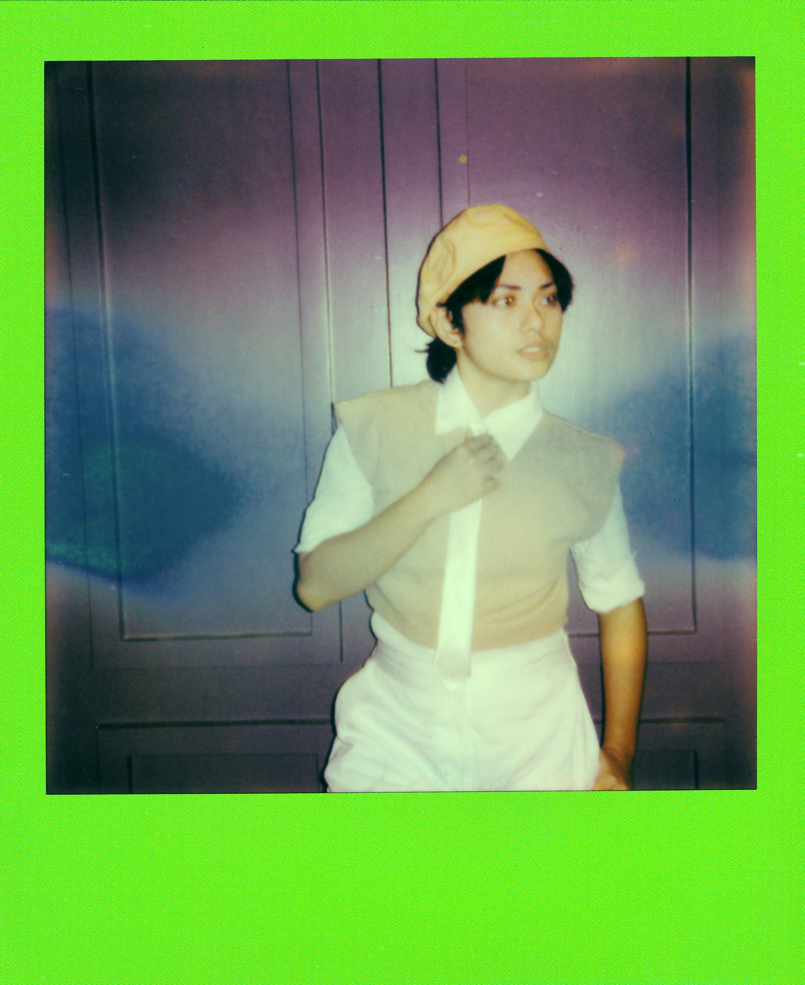 A person in a hat and vest adjusting their shirt.