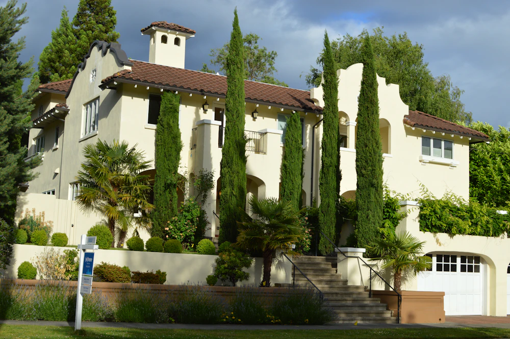 Elegant whitewashed villa with terracotta roof framed by tall cypresses