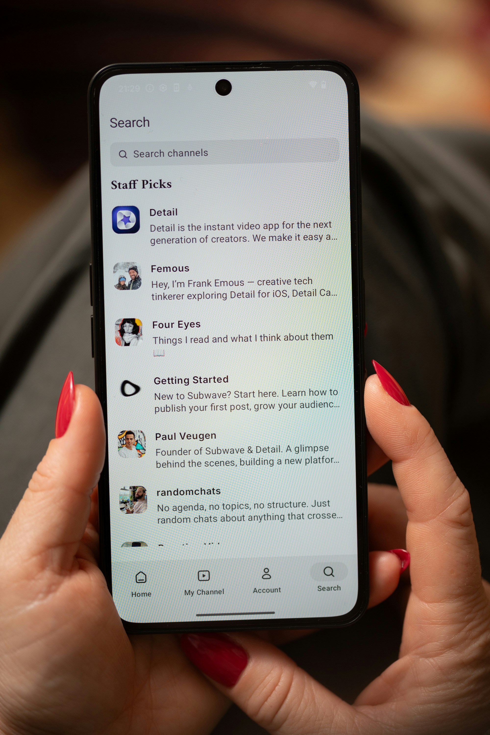Wanita memegang smartphone yang menampilkan daftar saluran.