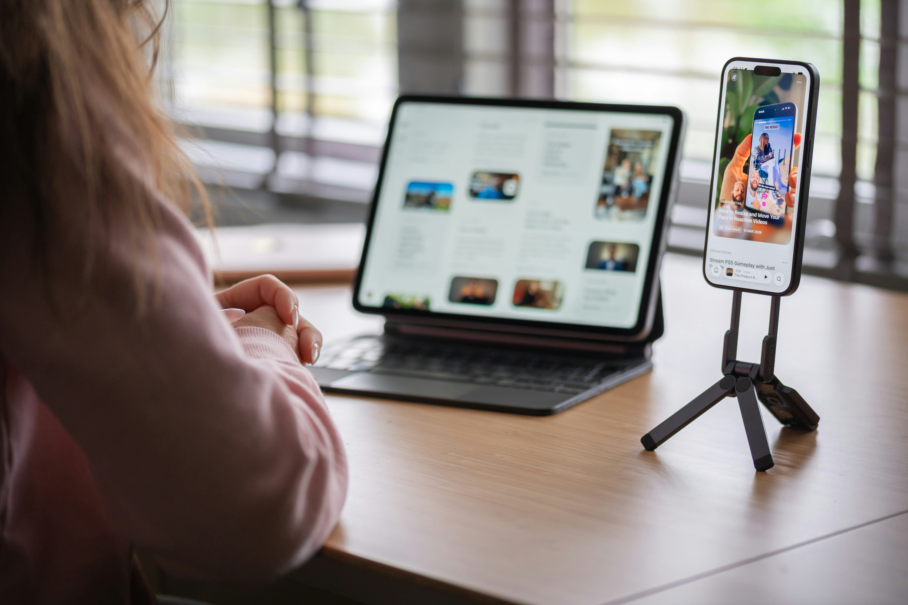 Person using tablet and smartphone on a wooden desk.