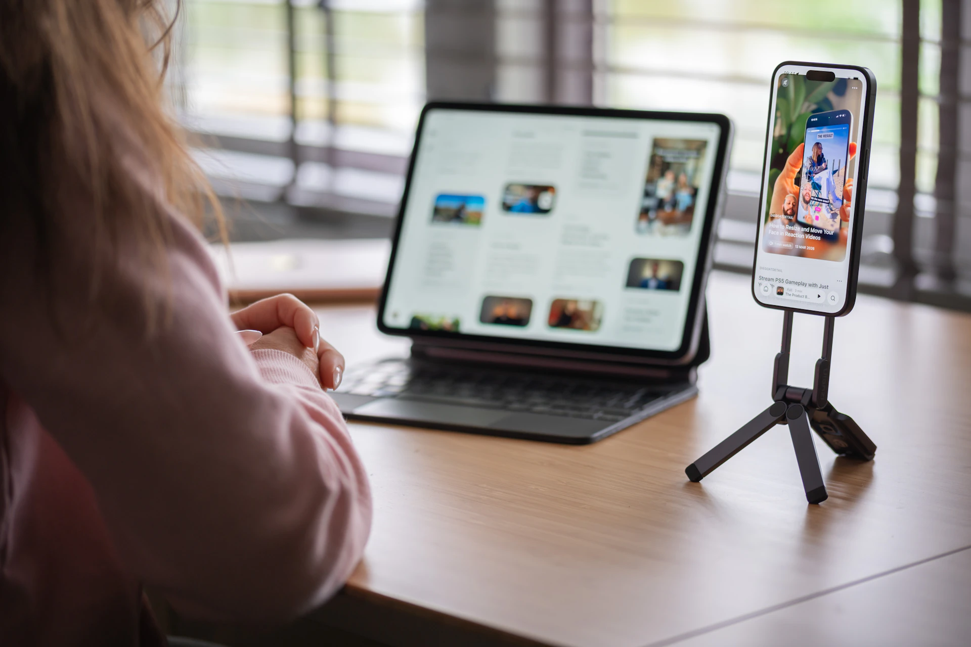 Person using tablet and smartphone on a wooden desk