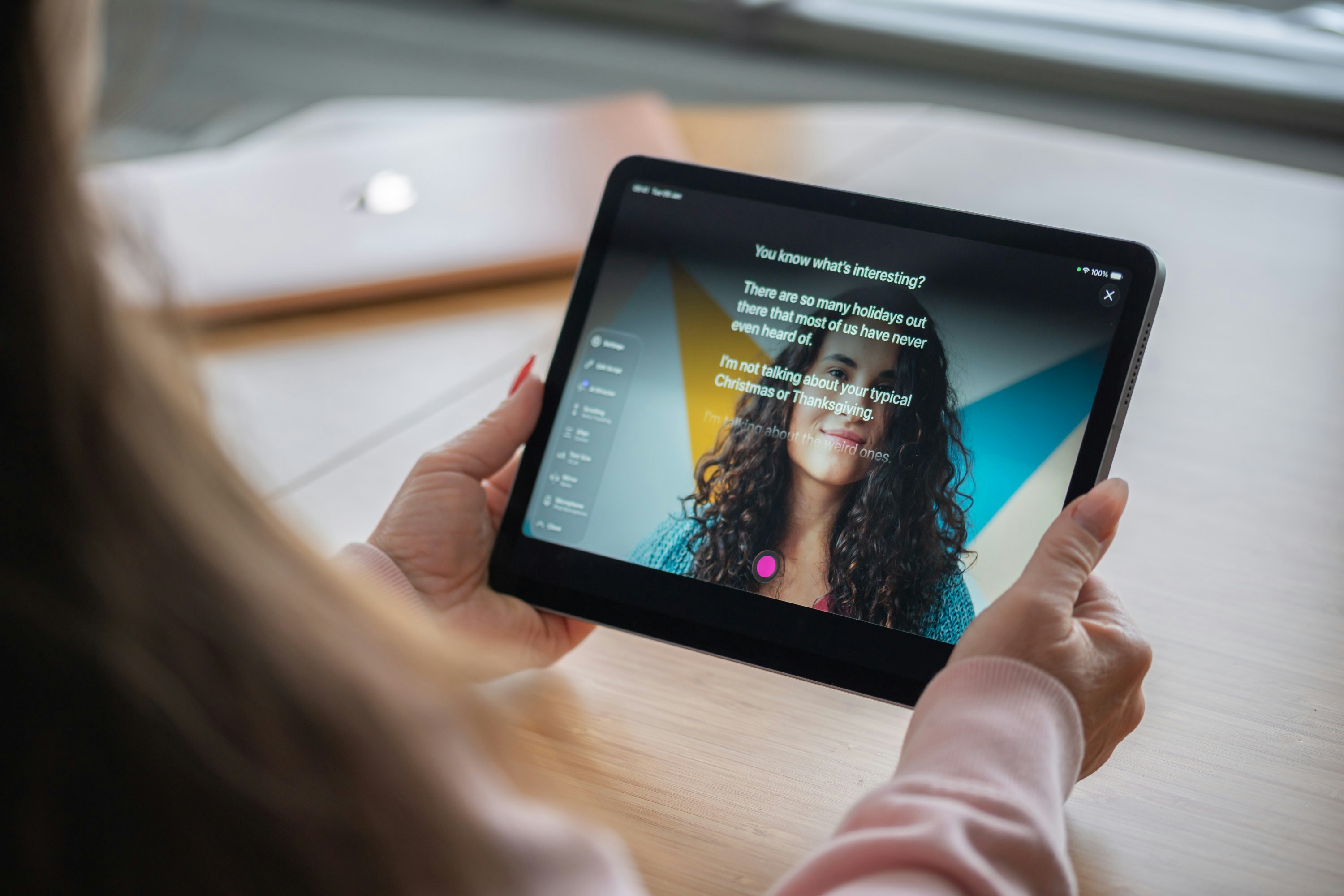 Wanita memegang tablet digital yang menunjukkan seorang wanita tersenyum.