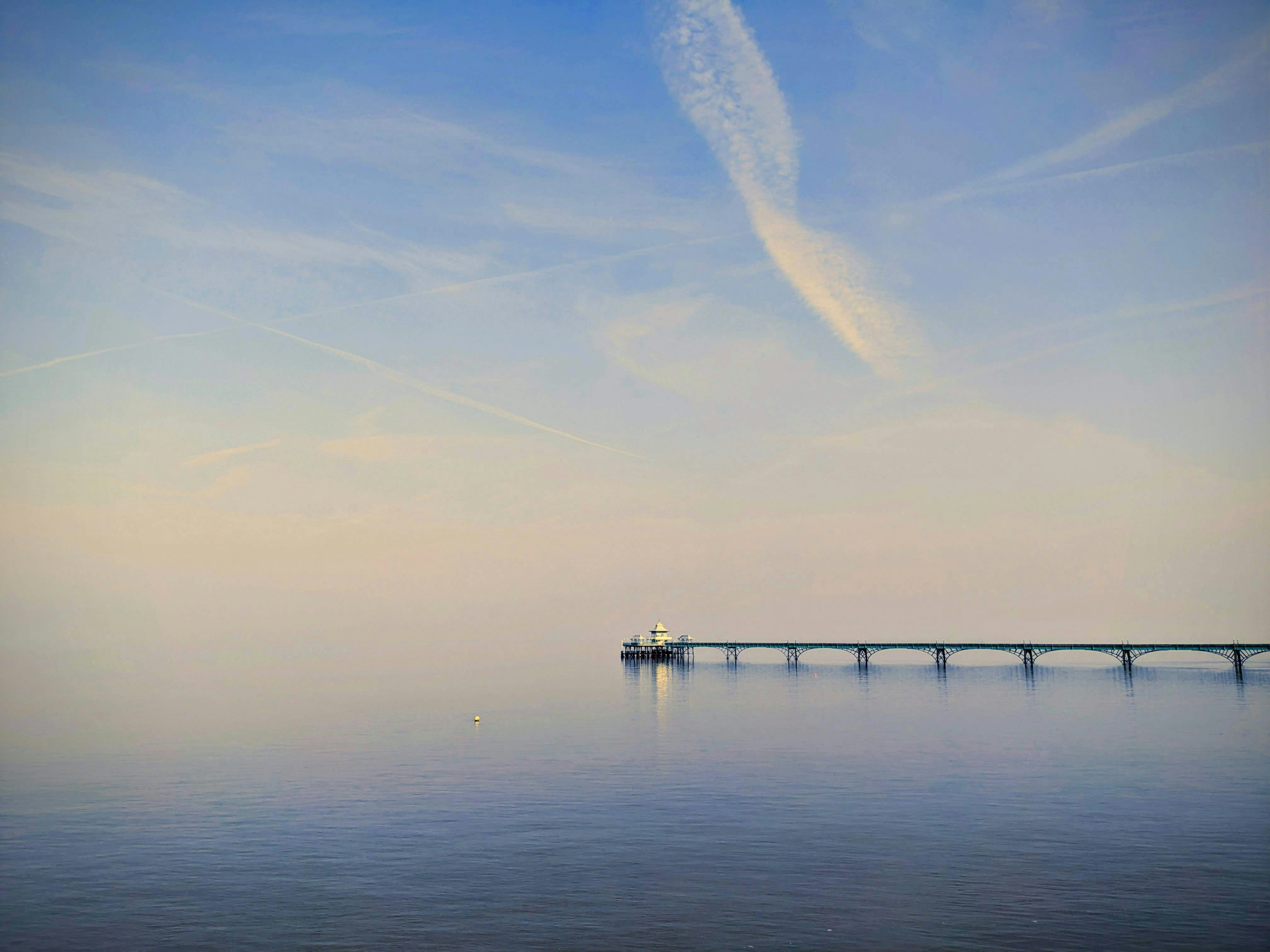 Pier extending into calm water under a serene blue sky