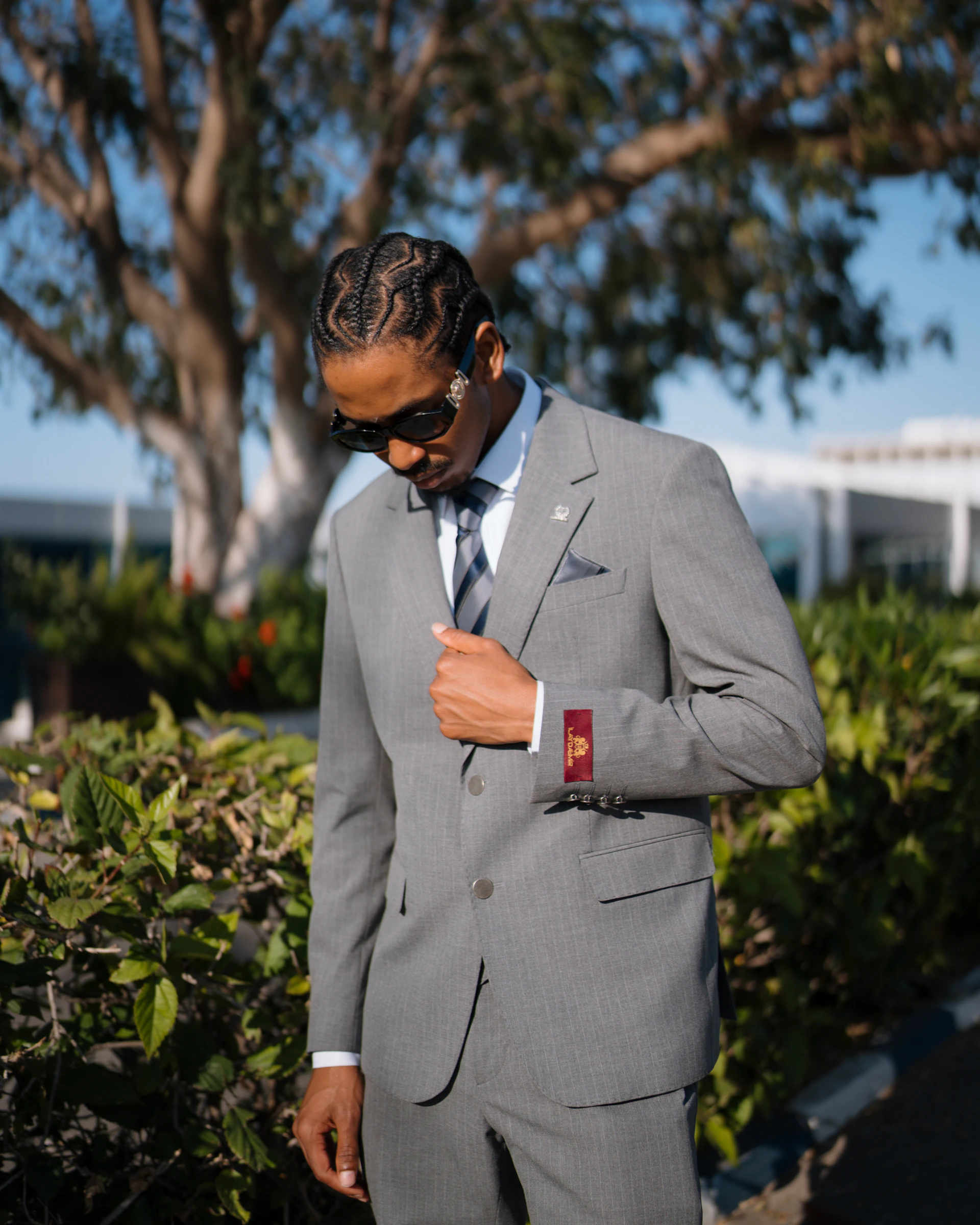 Stylish man in a grey suit and sunglasses outdoors.