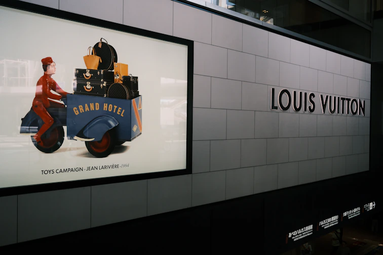 Louis vuitton sign and an advertisement for grand hotel luggage