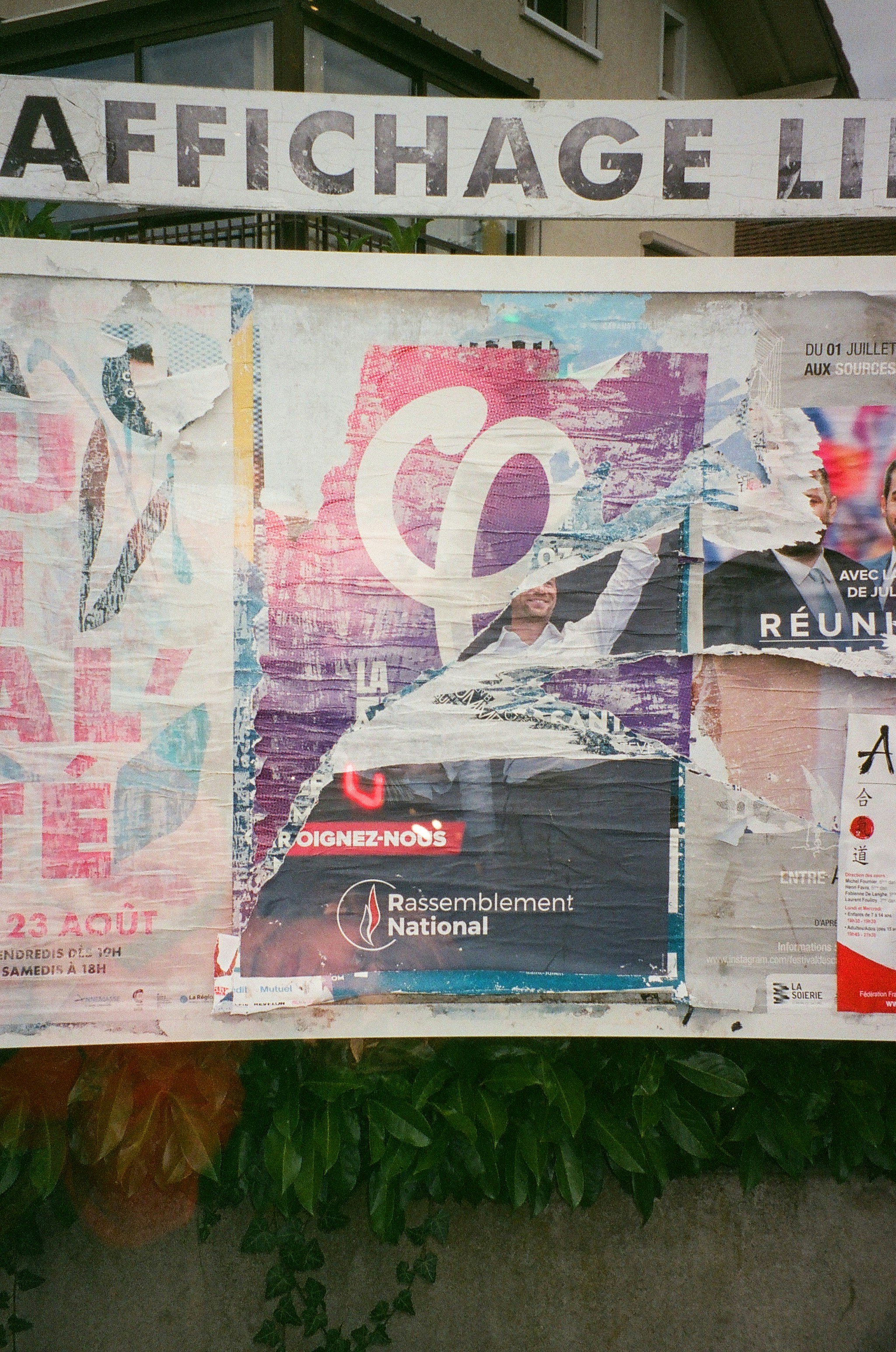 Tattered political posters cover a public bulletin board.