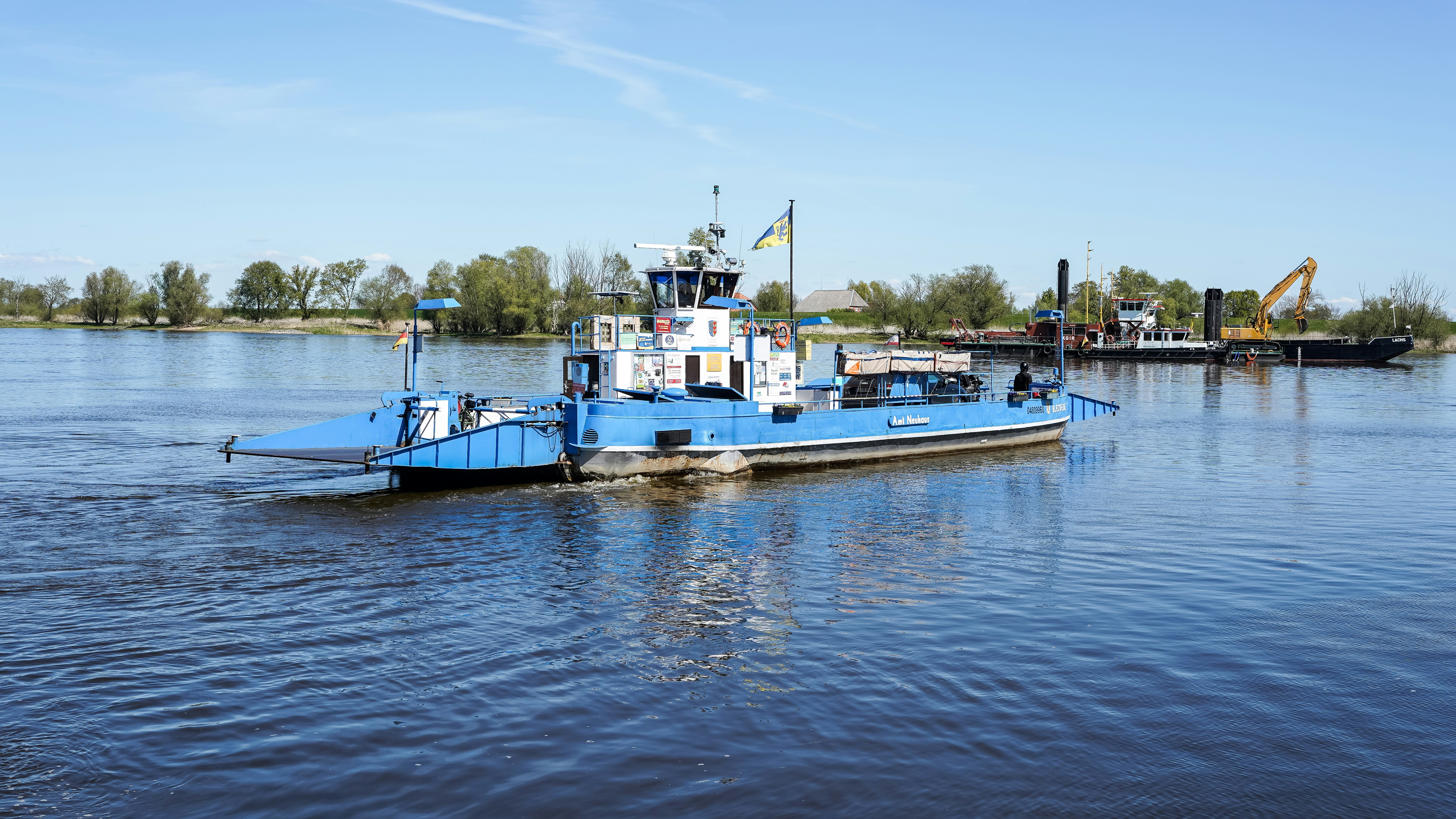 Blau-weiße Fähre segelt auf einem Fluss.