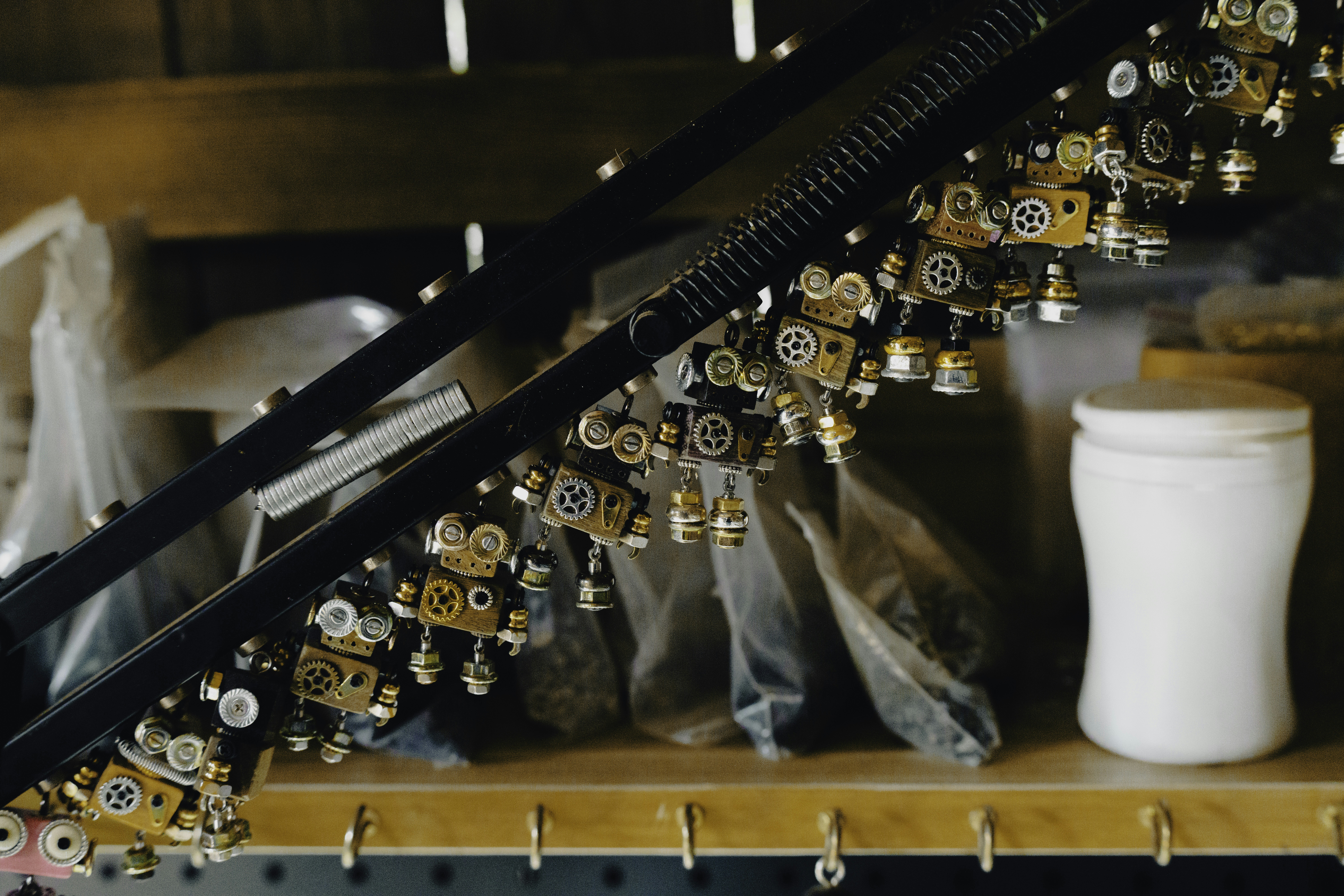 Steampunk robot charms made from metal gears hang in a workshop.