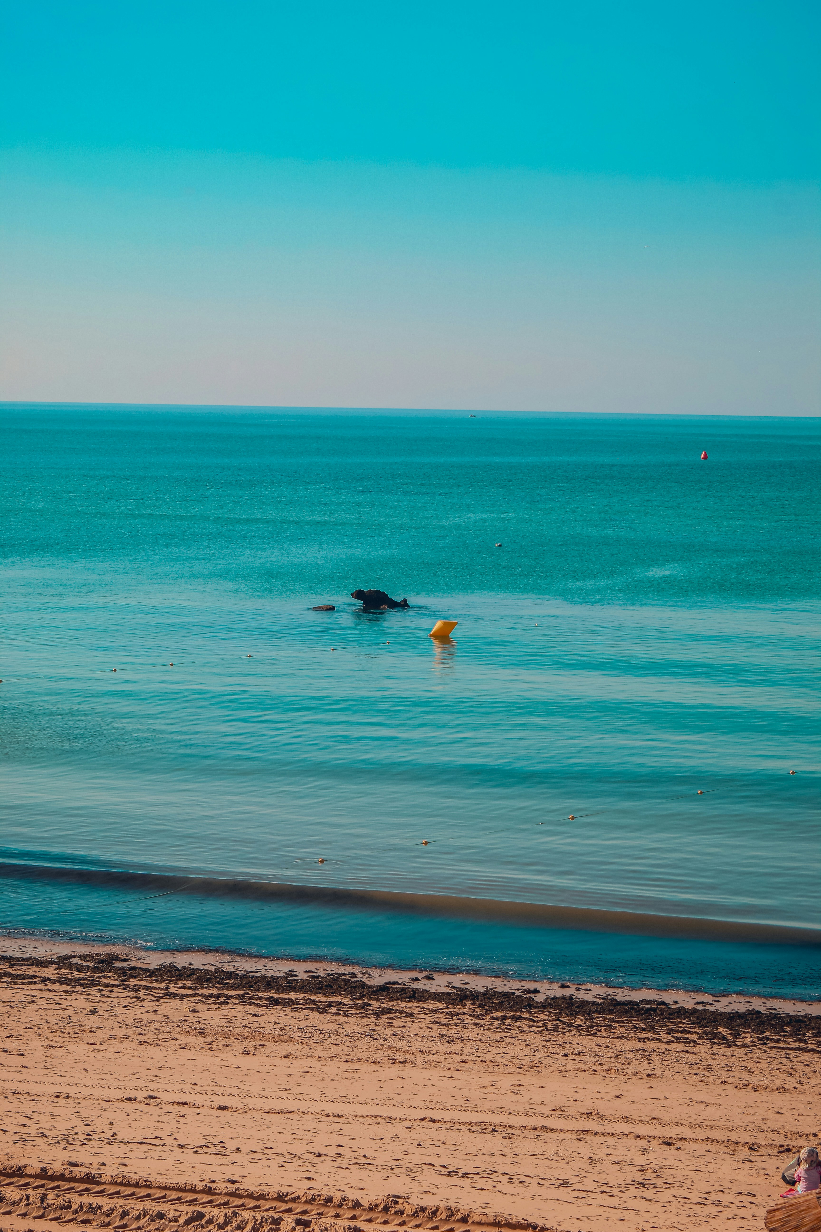 Mar turquesa, praia de areia e céu azul claro.