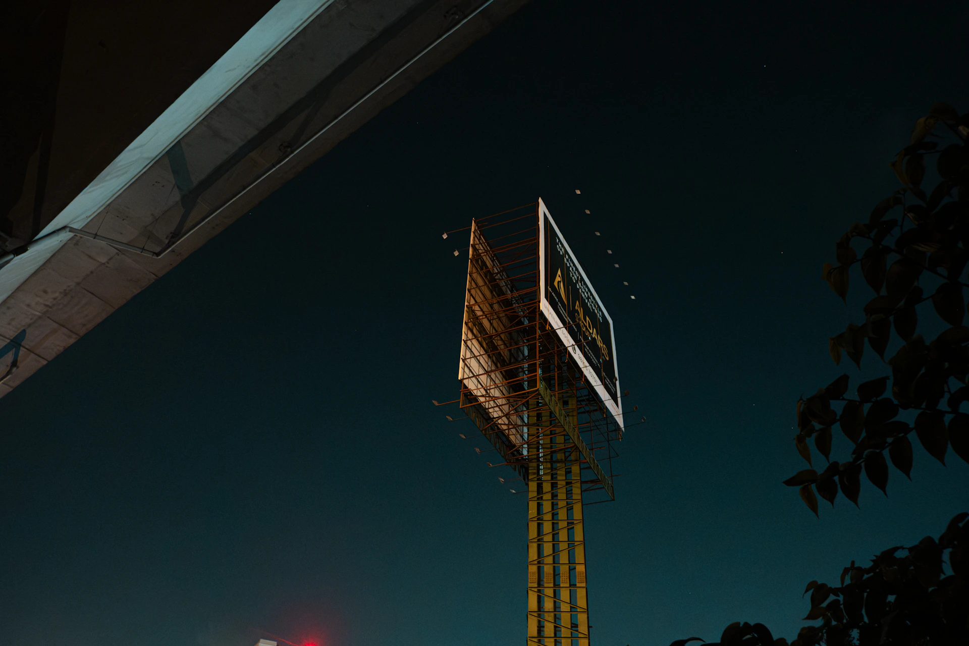 A tall, illuminated billboard stands against a dark night sky.