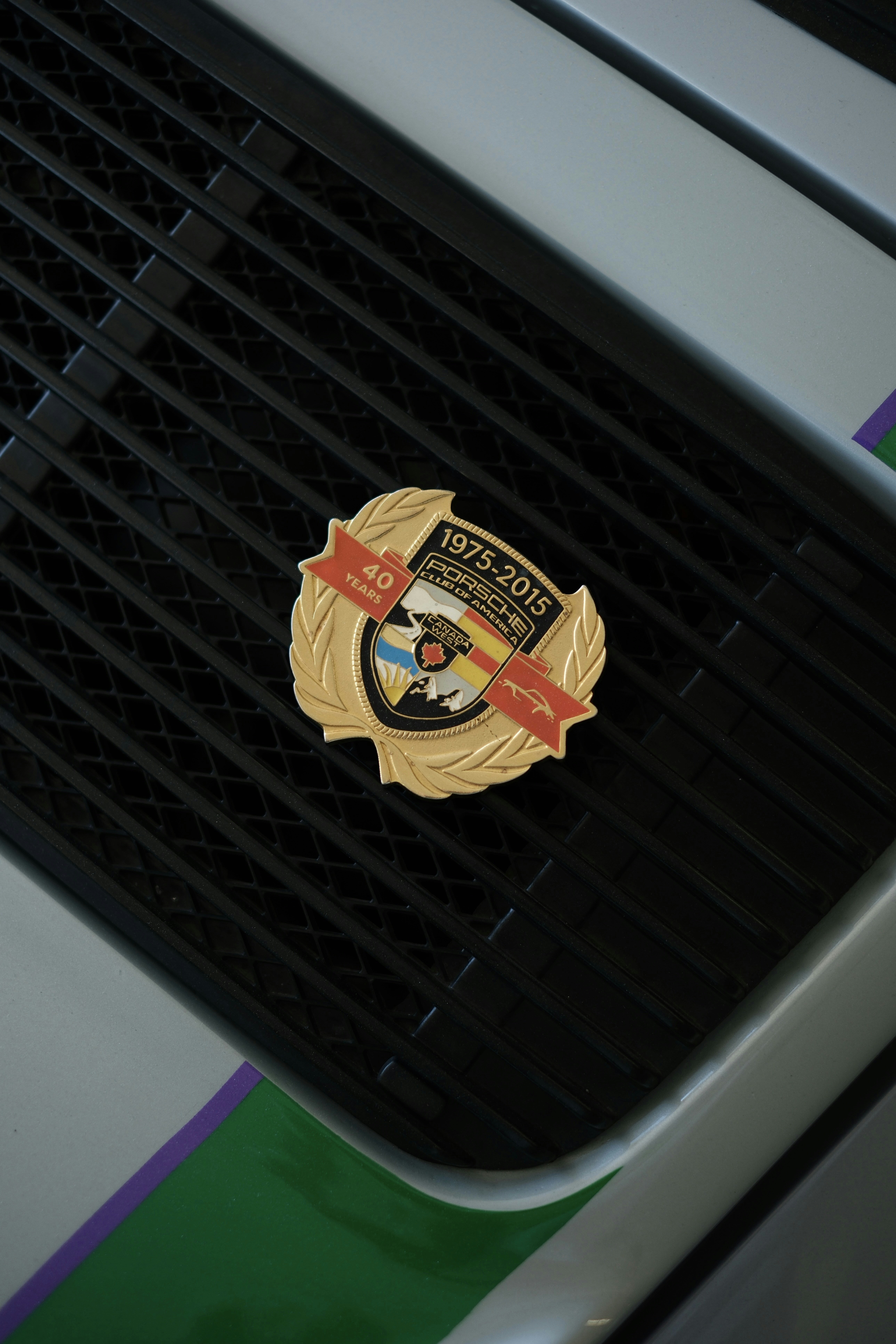 Emblème doré du 40e anniversaire de la Porsche sur la calandre d’une voiture.