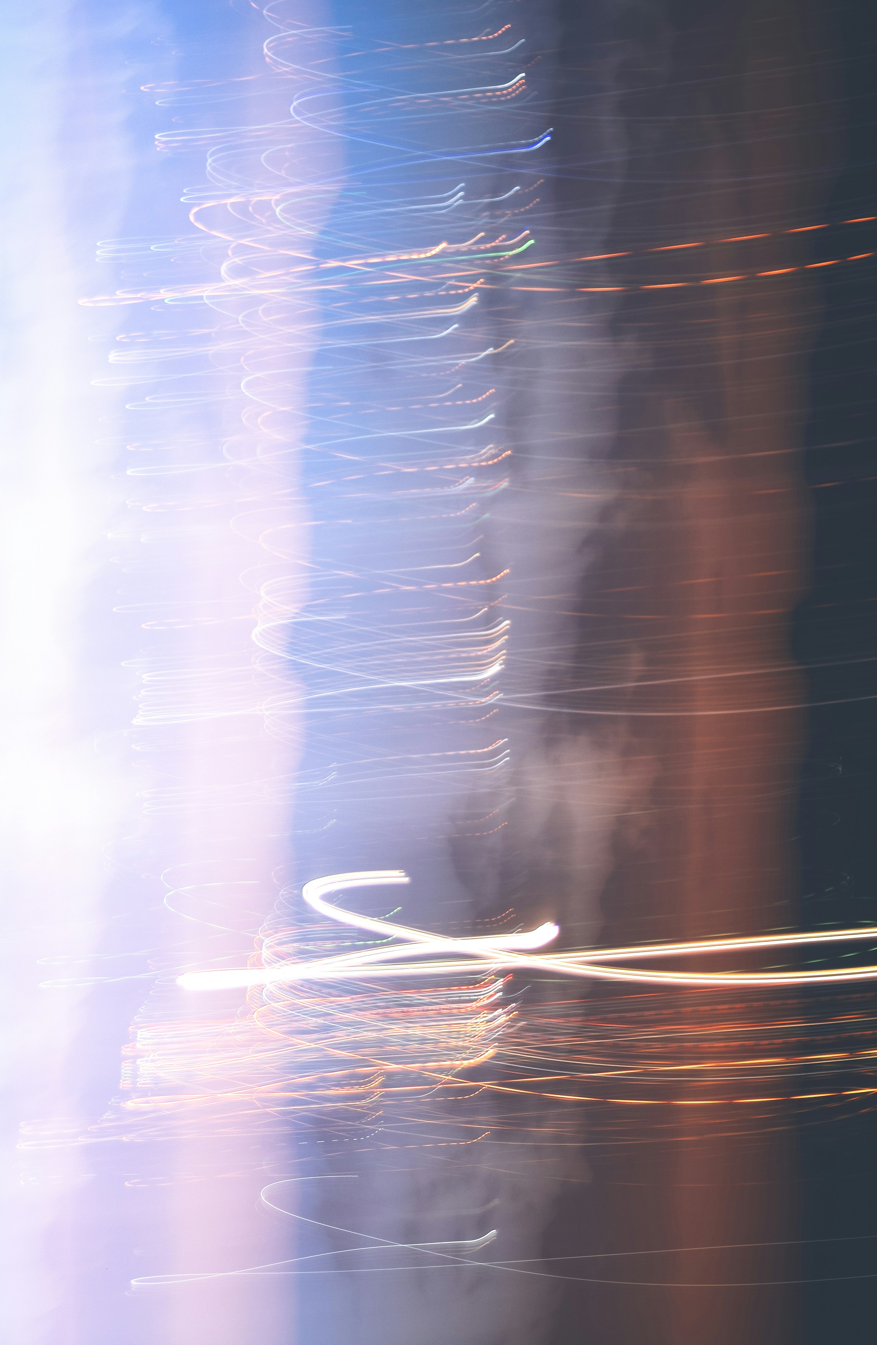 Des traînées de lumière abstraite sur un fond flou bleu et orange.