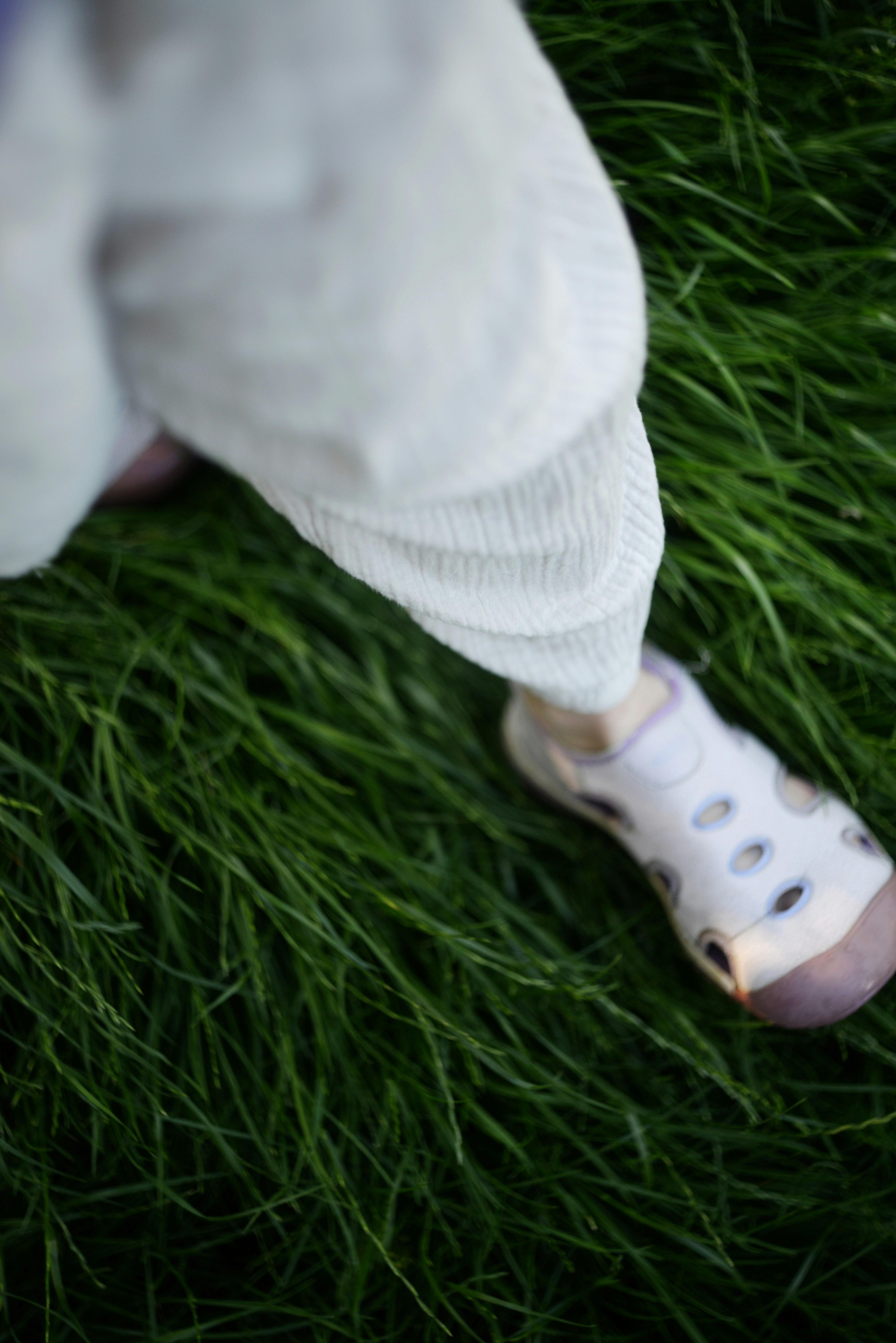 Child wearing sandals while walking through soft green grass